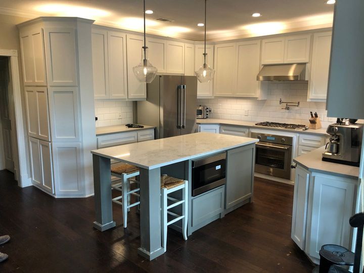 A kitchen with white cabinets and a large island in the middle.