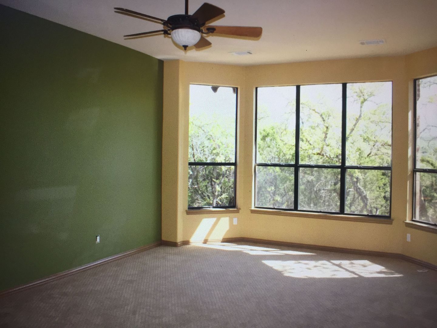 An empty room with a ceiling fan and lots of windows