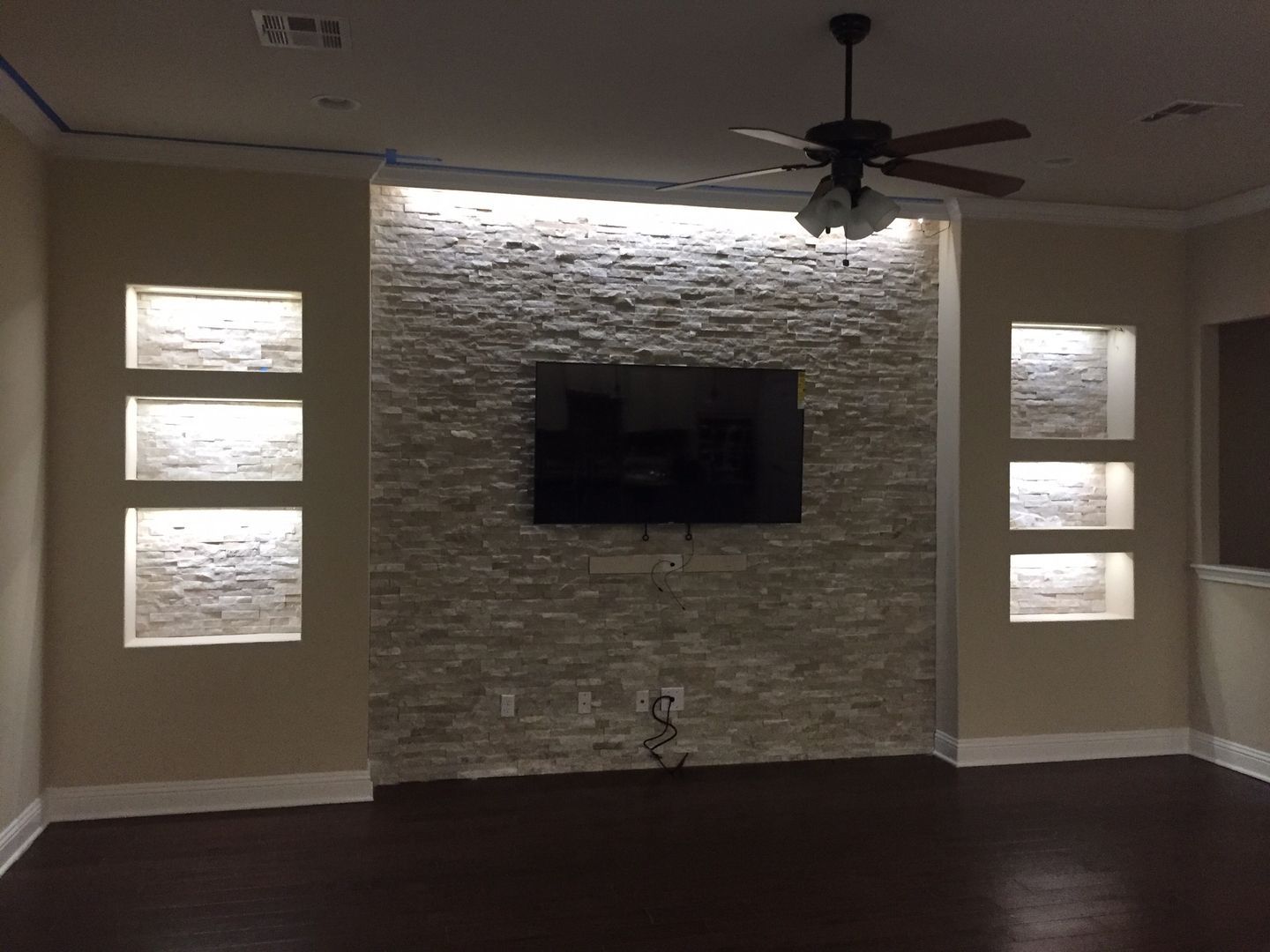 A living room with a ceiling fan and a flat screen tv