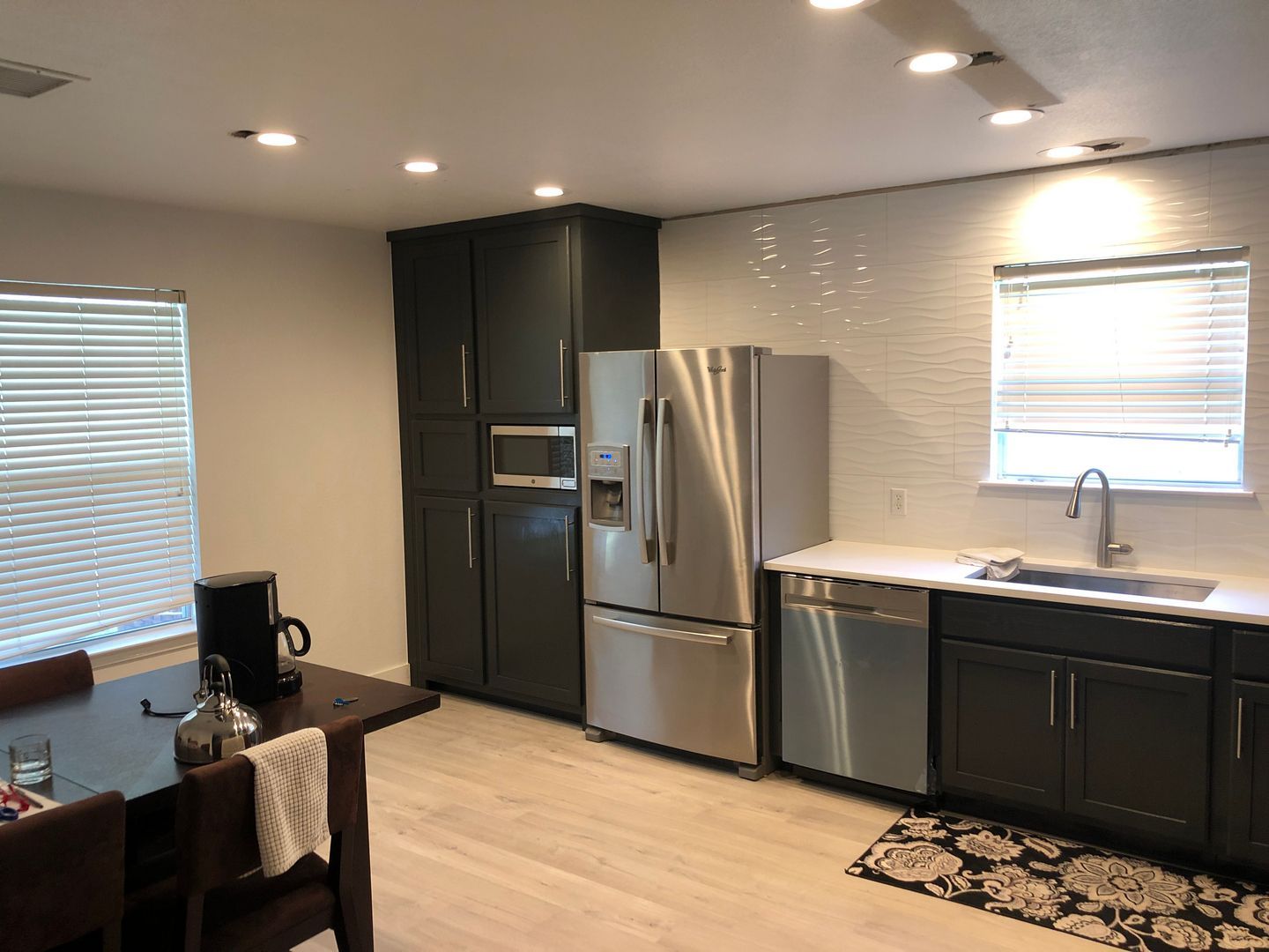 A kitchen with stainless steel appliances , a refrigerator , a sink , and a table.