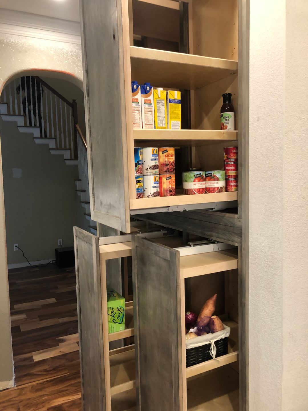 A pantry with a sliding door and shelves filled with food.