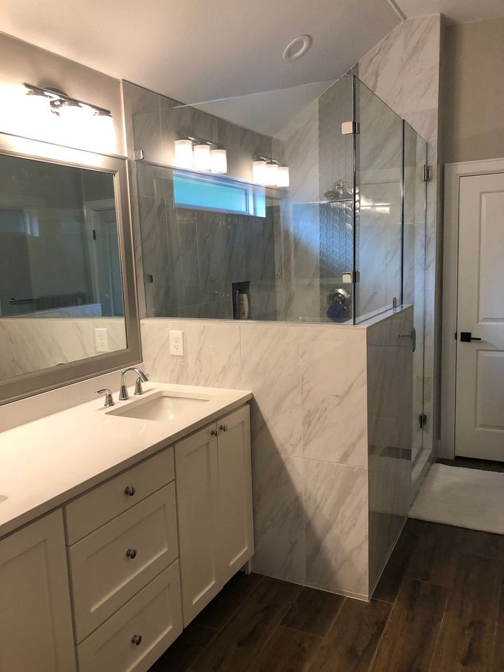 A bathroom with a sink , mirror and walk in shower.