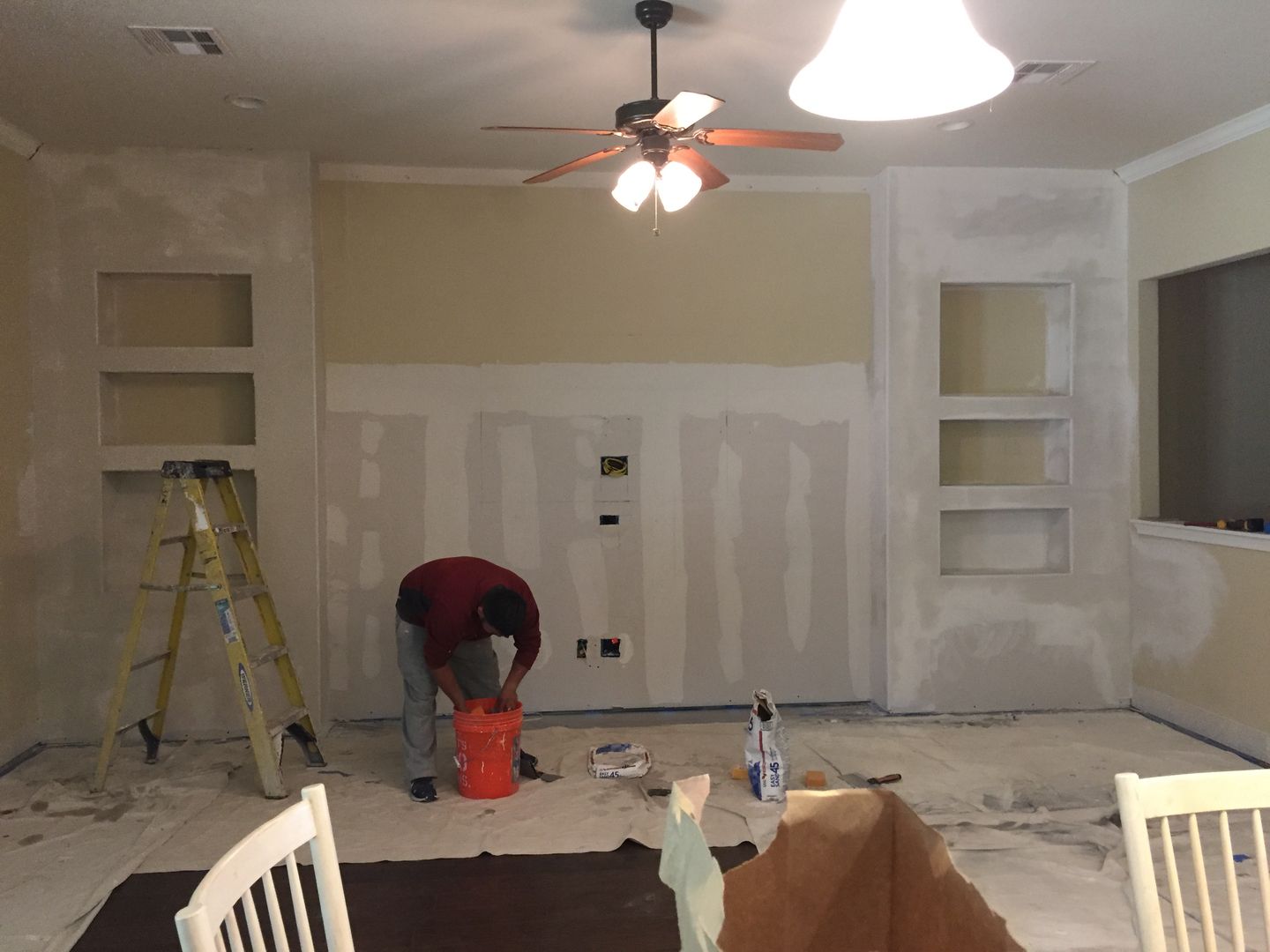 A man is painting a wall in a living room