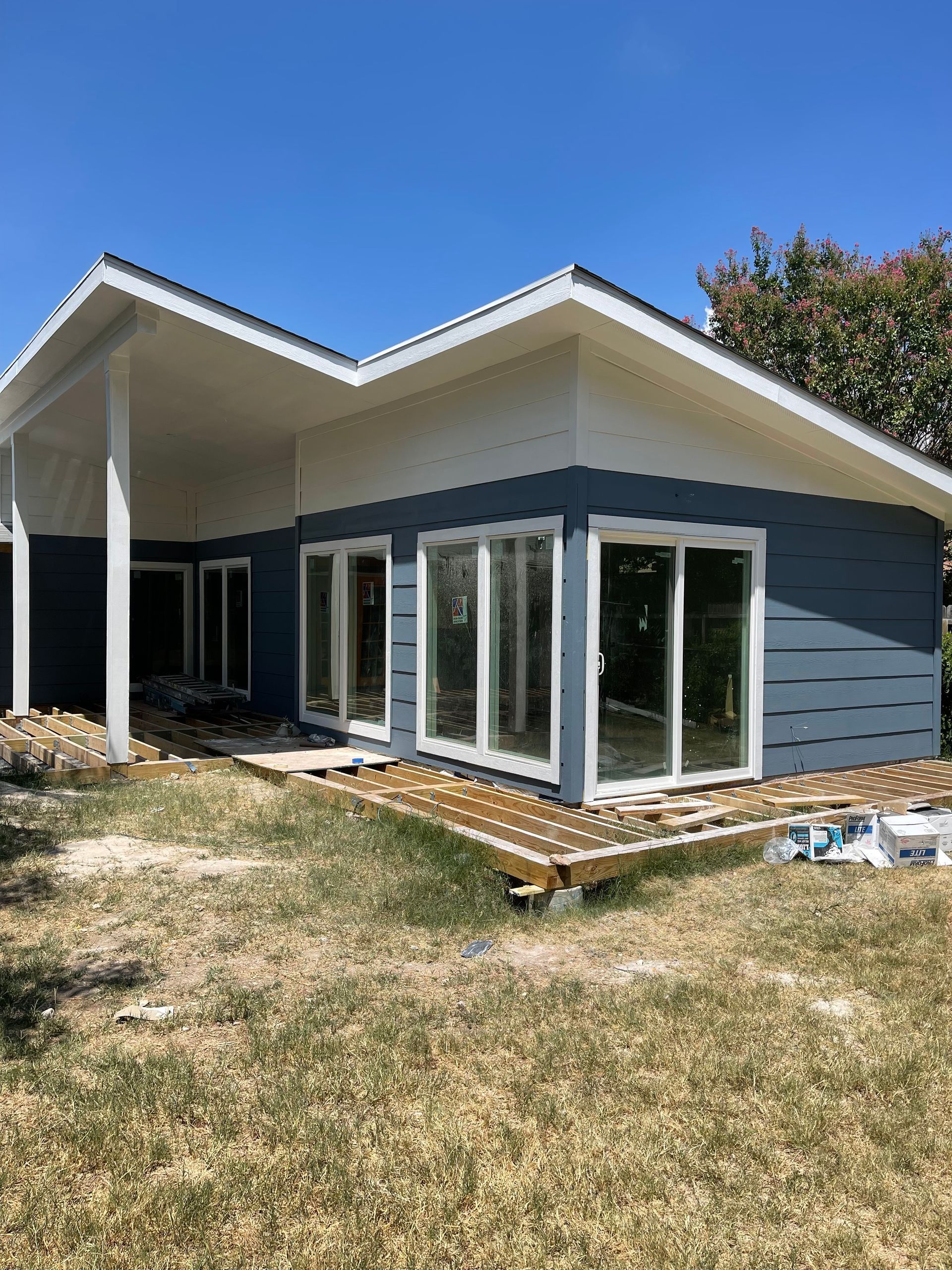 A small house with a lot of windows is sitting on top of a lush green field.