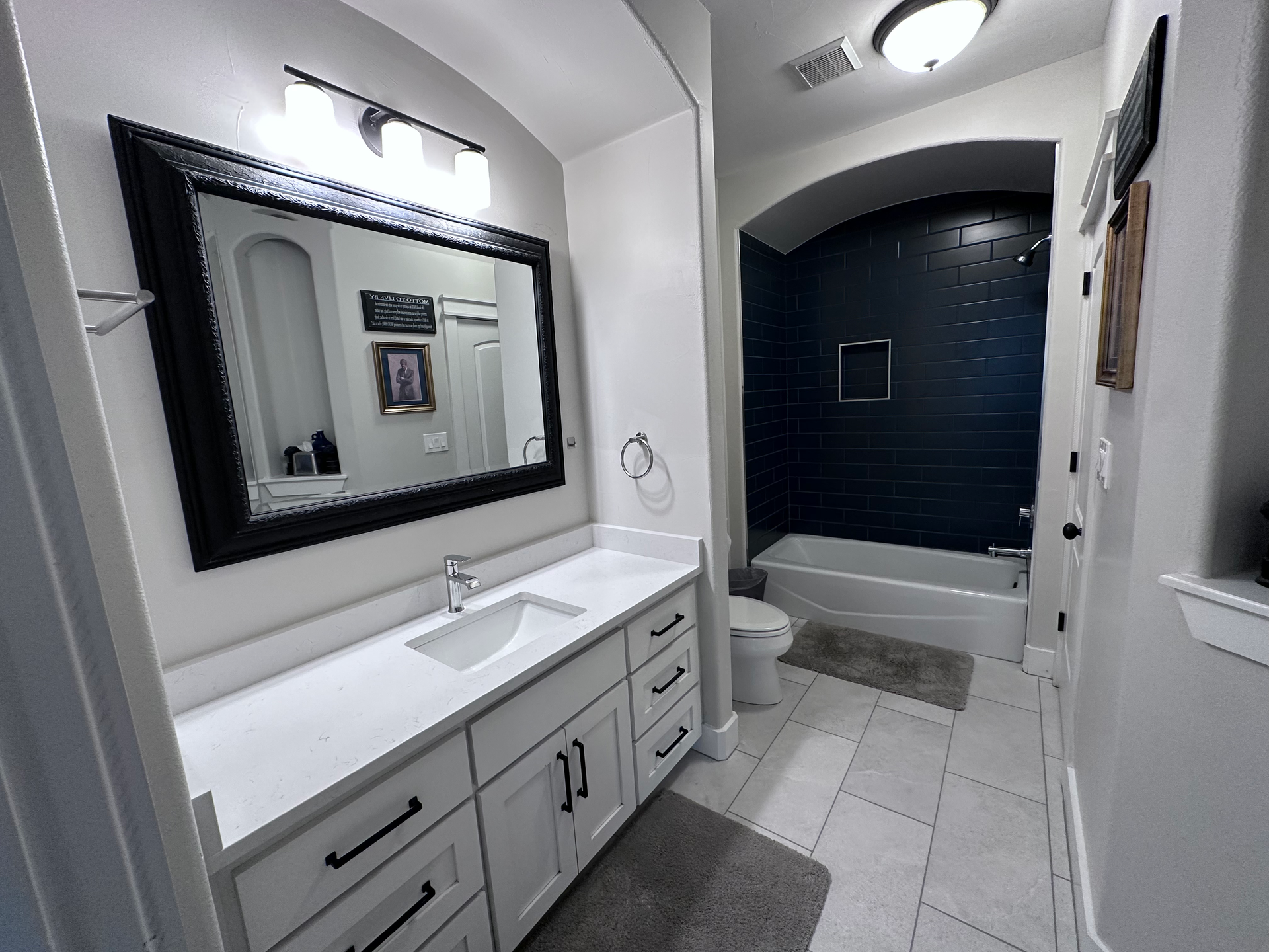 A bathroom with a sink , toilet , shower and mirror.