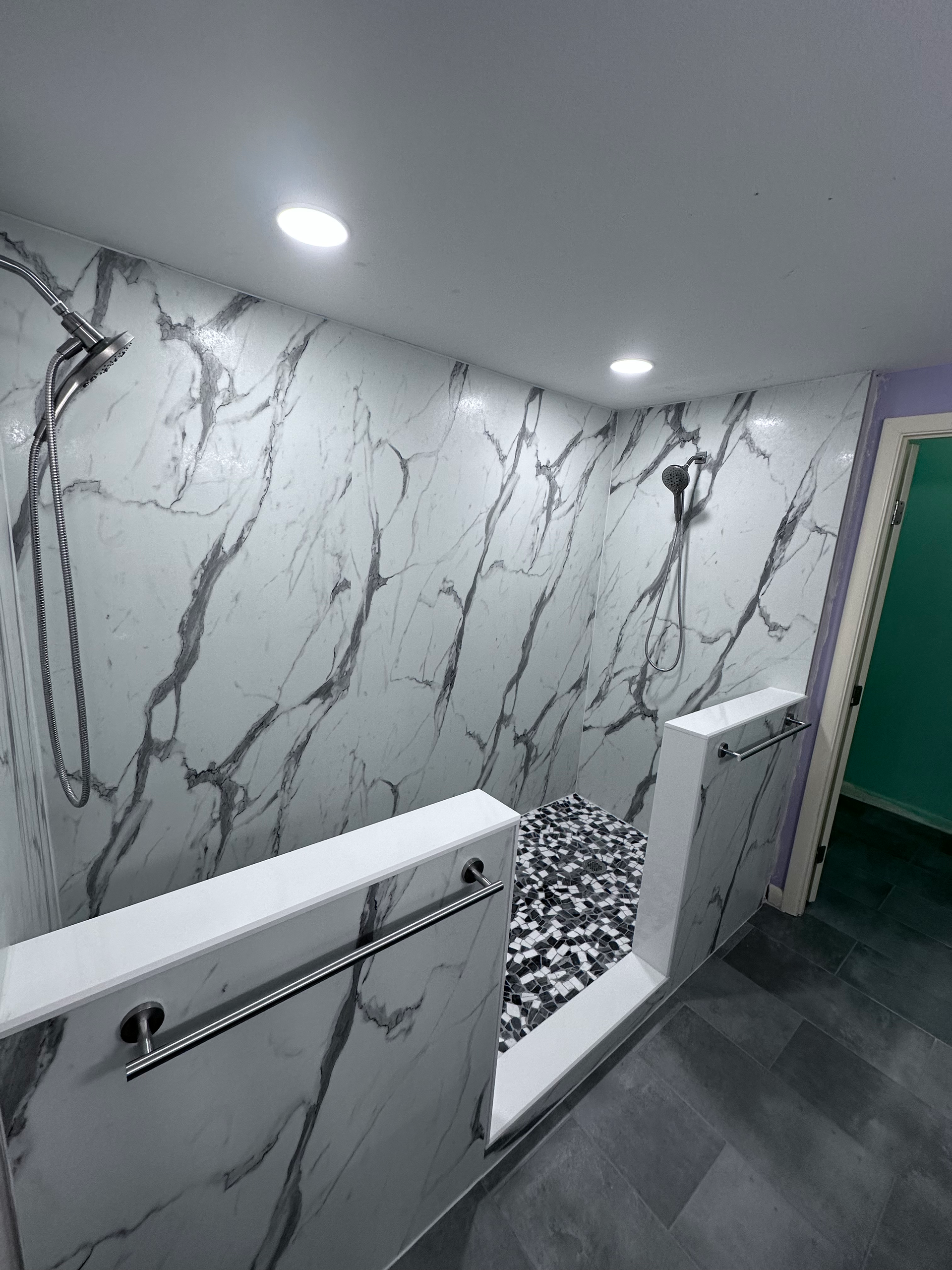 A bathroom with marble walls and a walk in shower.