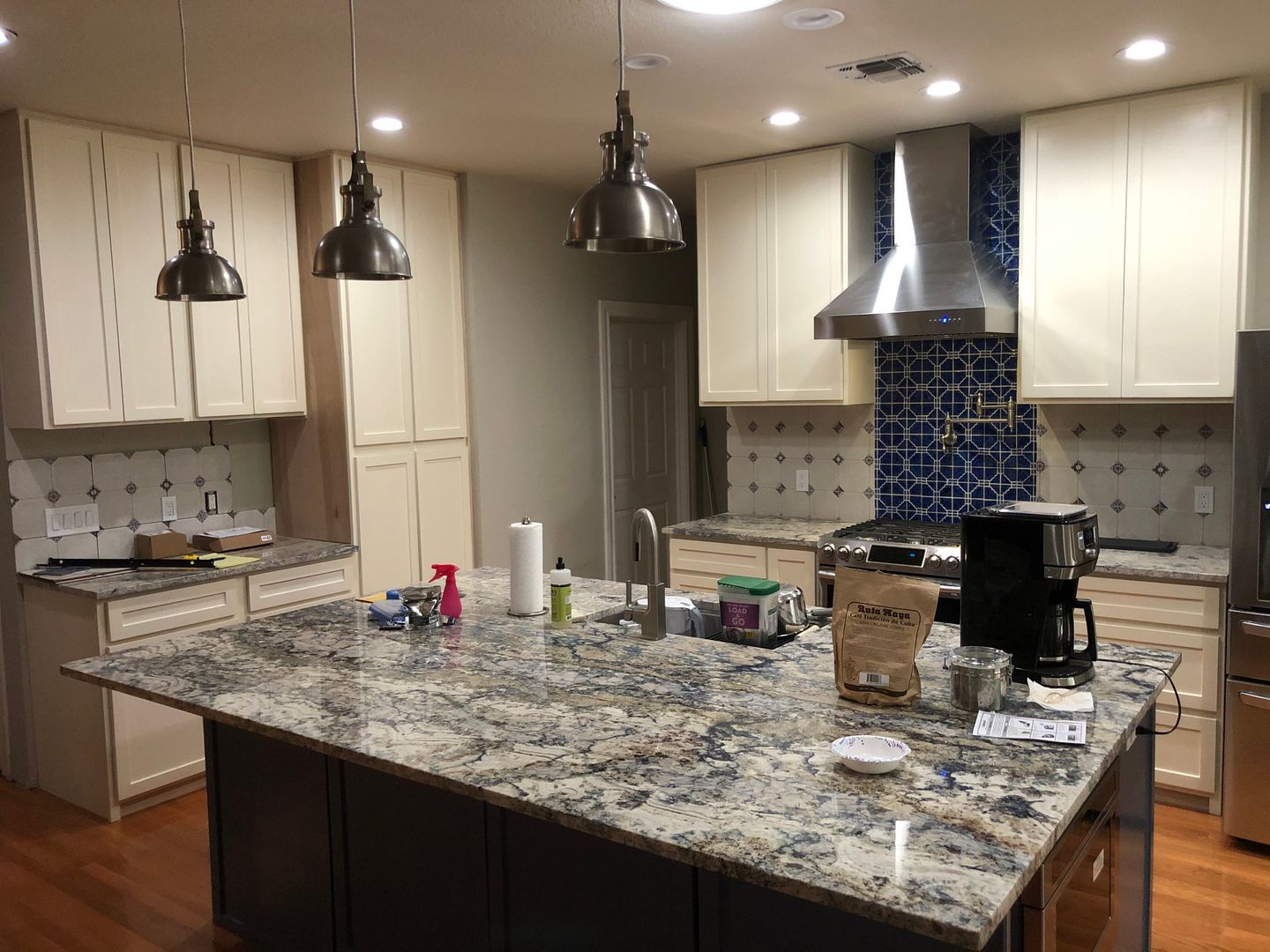 A kitchen with granite counter tops , stainless steel appliances , and white cabinets.