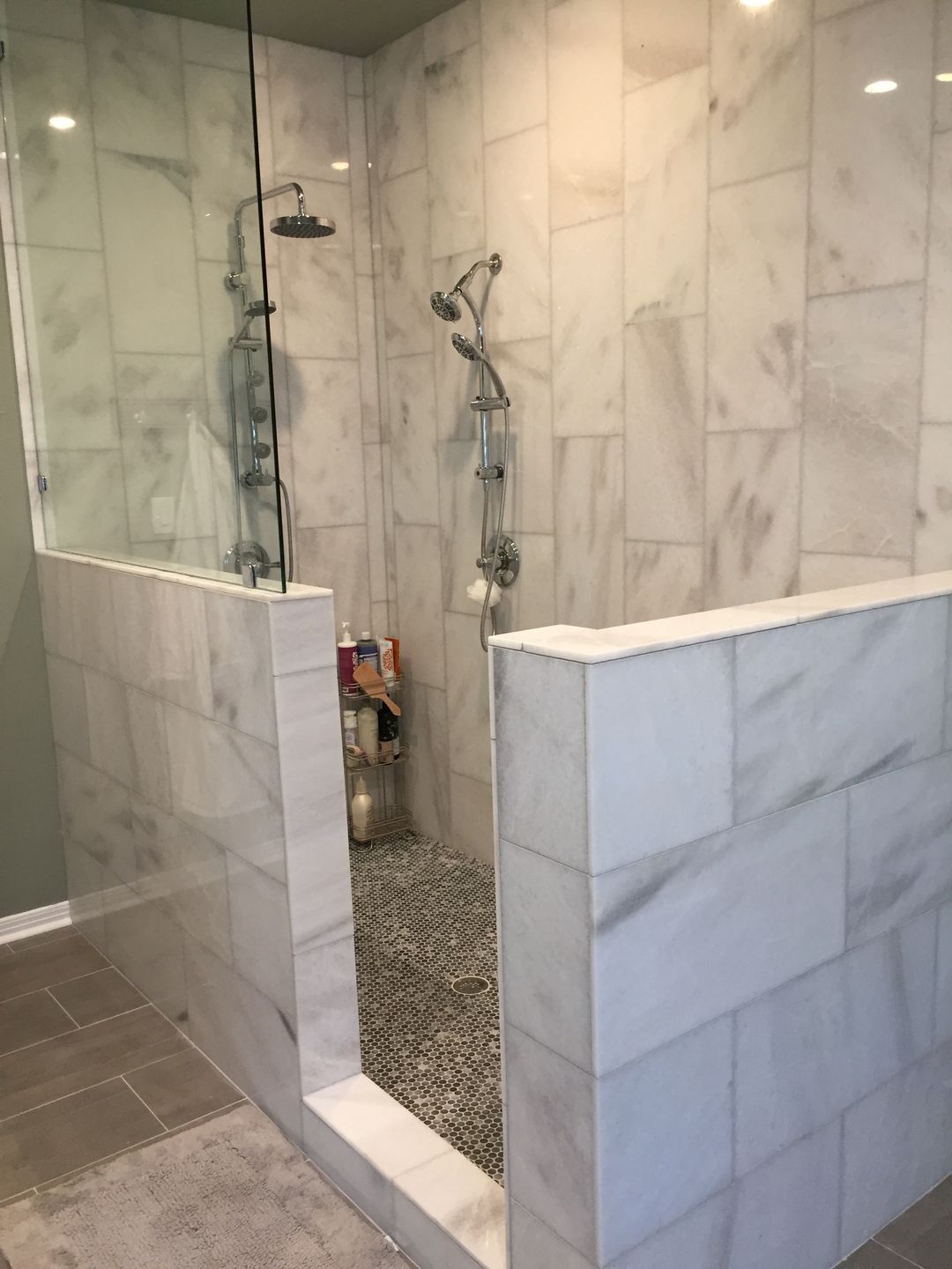 A bathroom with marble tiles and a walk in shower with a glass door.
