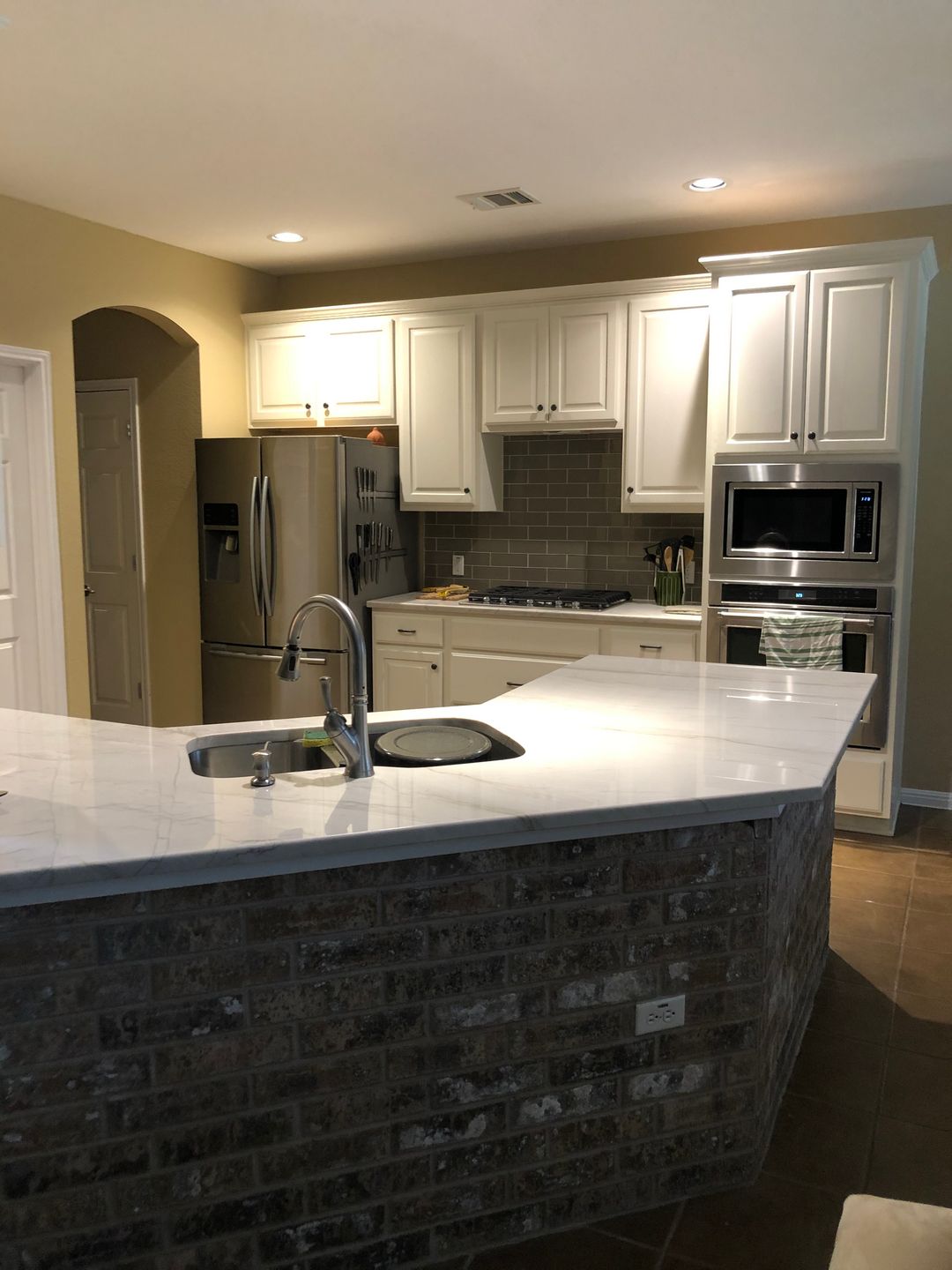 A kitchen with white cabinets and a brick counter top
