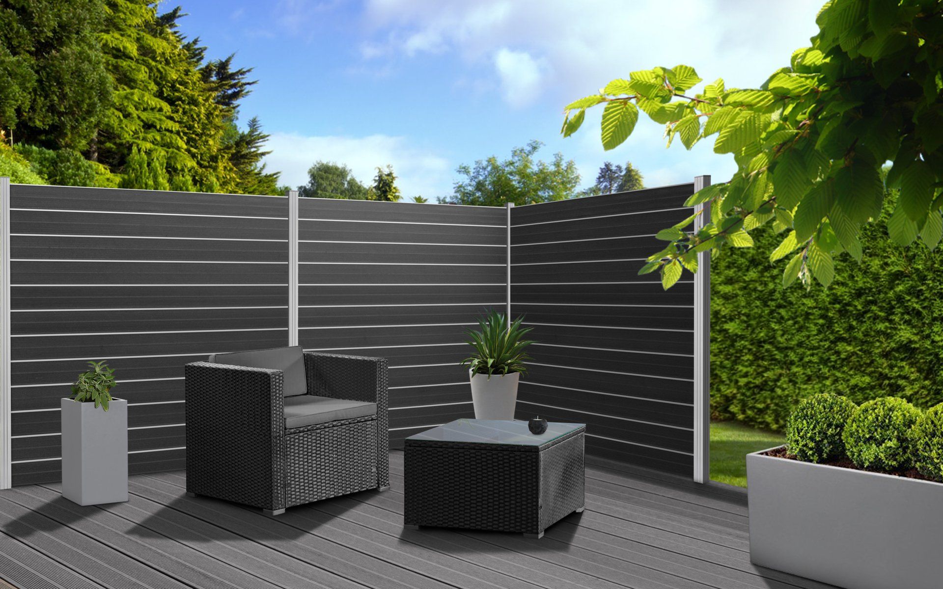 Eine Terrasse mit Zaun, Stühlen und einem Tisch