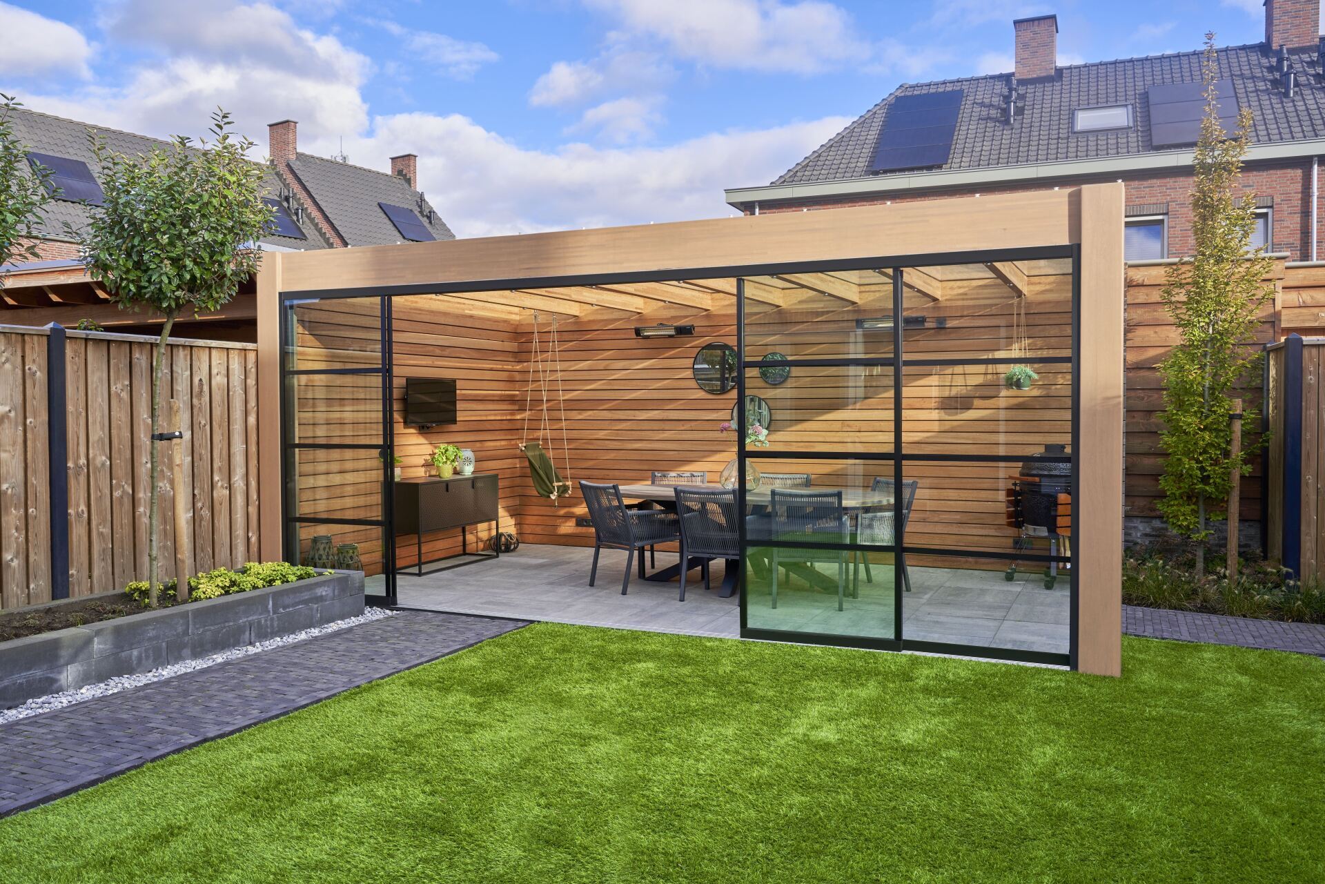Eine Terrasse mit einem Tisch und Stühlen unter einer Pergola in einem Hinterhof.