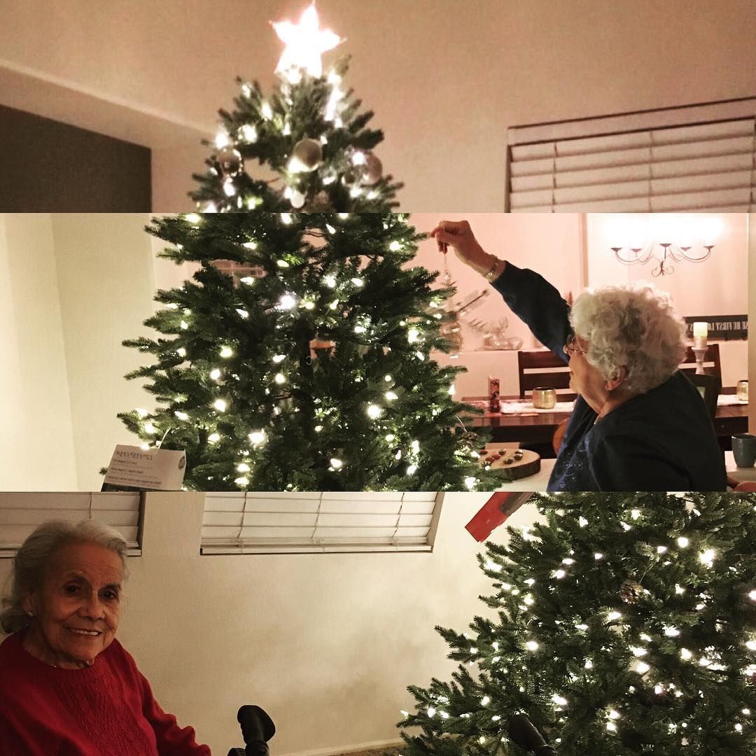 A woman decorates a christmas tree with a star on top