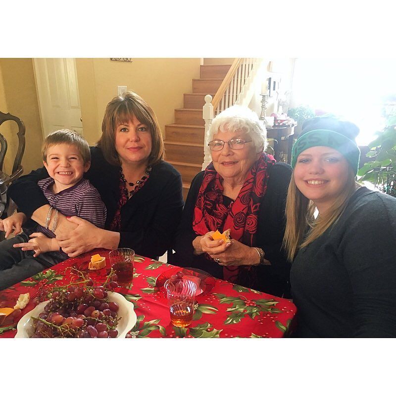 Three women and a child are sitting at a table with grapes on it.