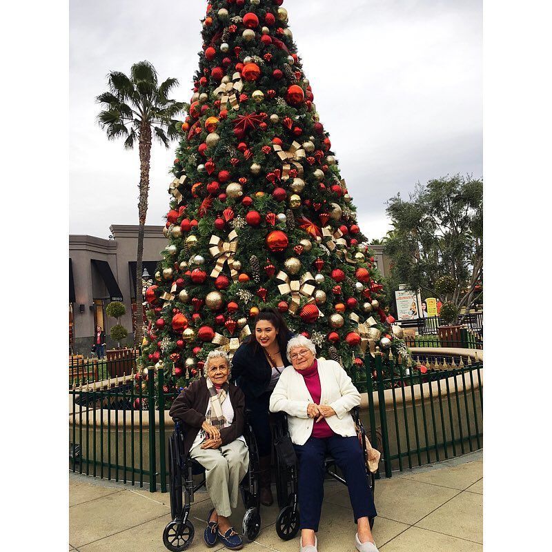 Three women are posing for a picture in front of a christmas tree.