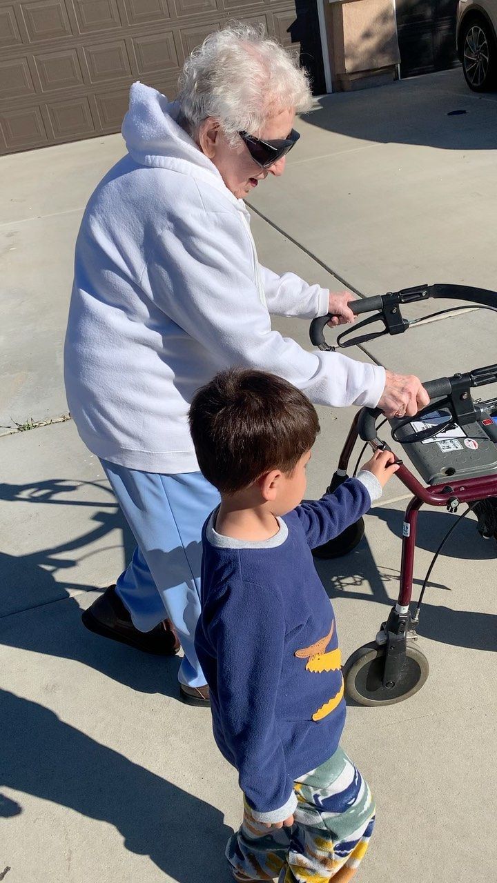 An elderly woman is teaching a young boy how to use a walker.