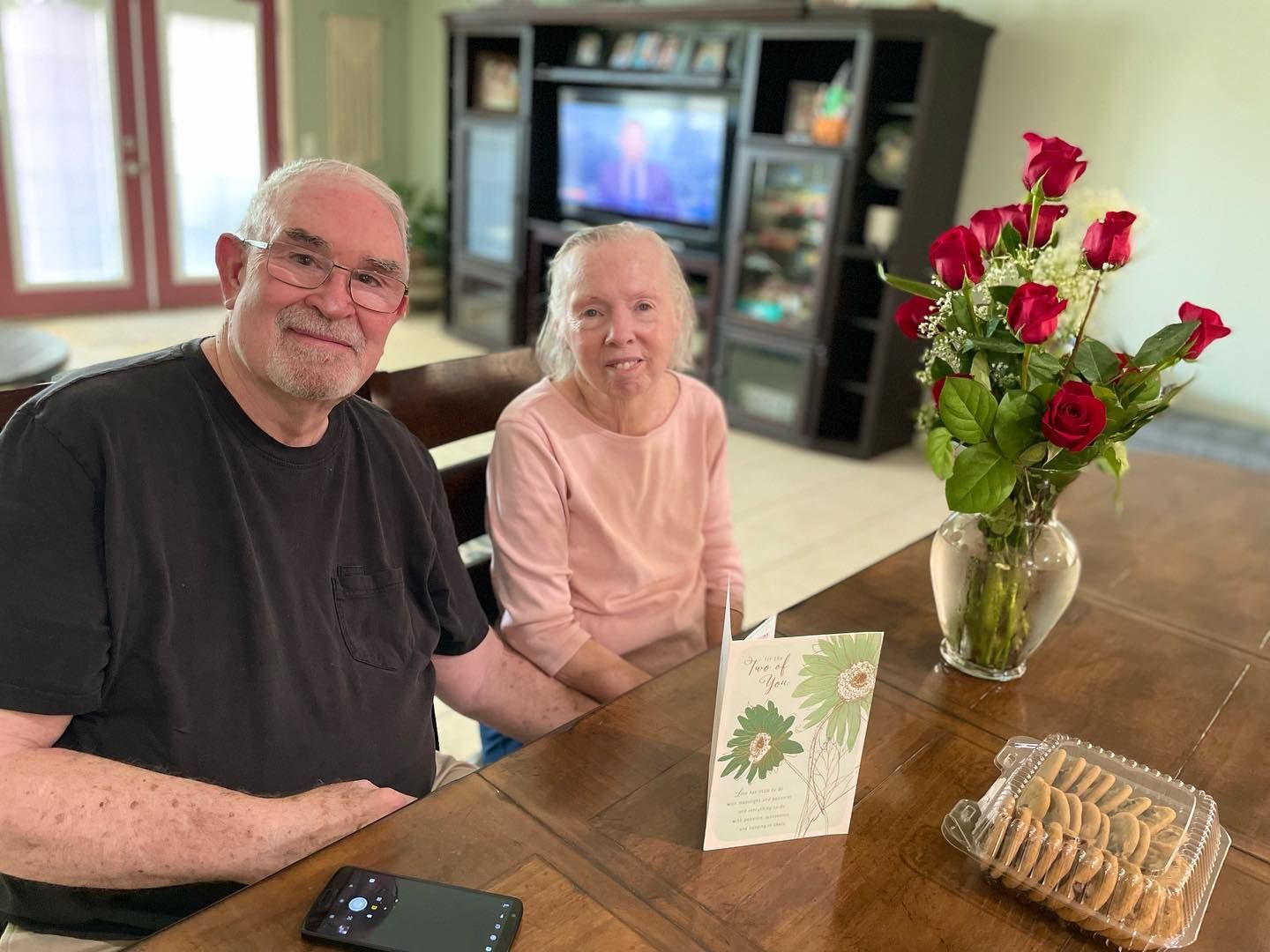 A man and a woman are sitting at a table in a living room.