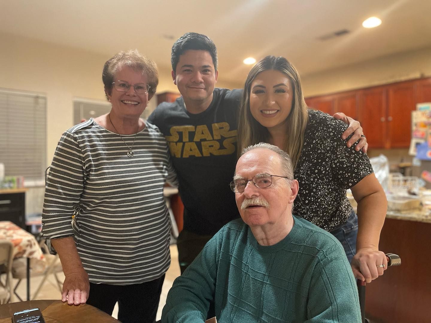 A man wearing a star wars shirt is posing for a picture with his family.