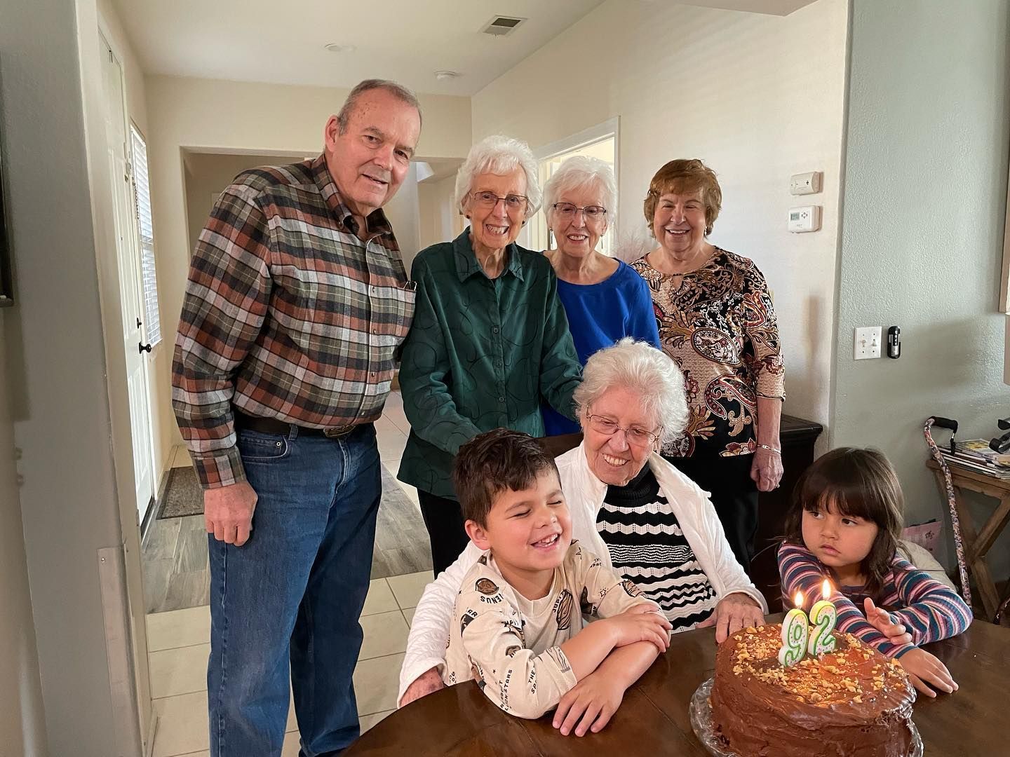A group of people are standing around a table with a cake and candles.