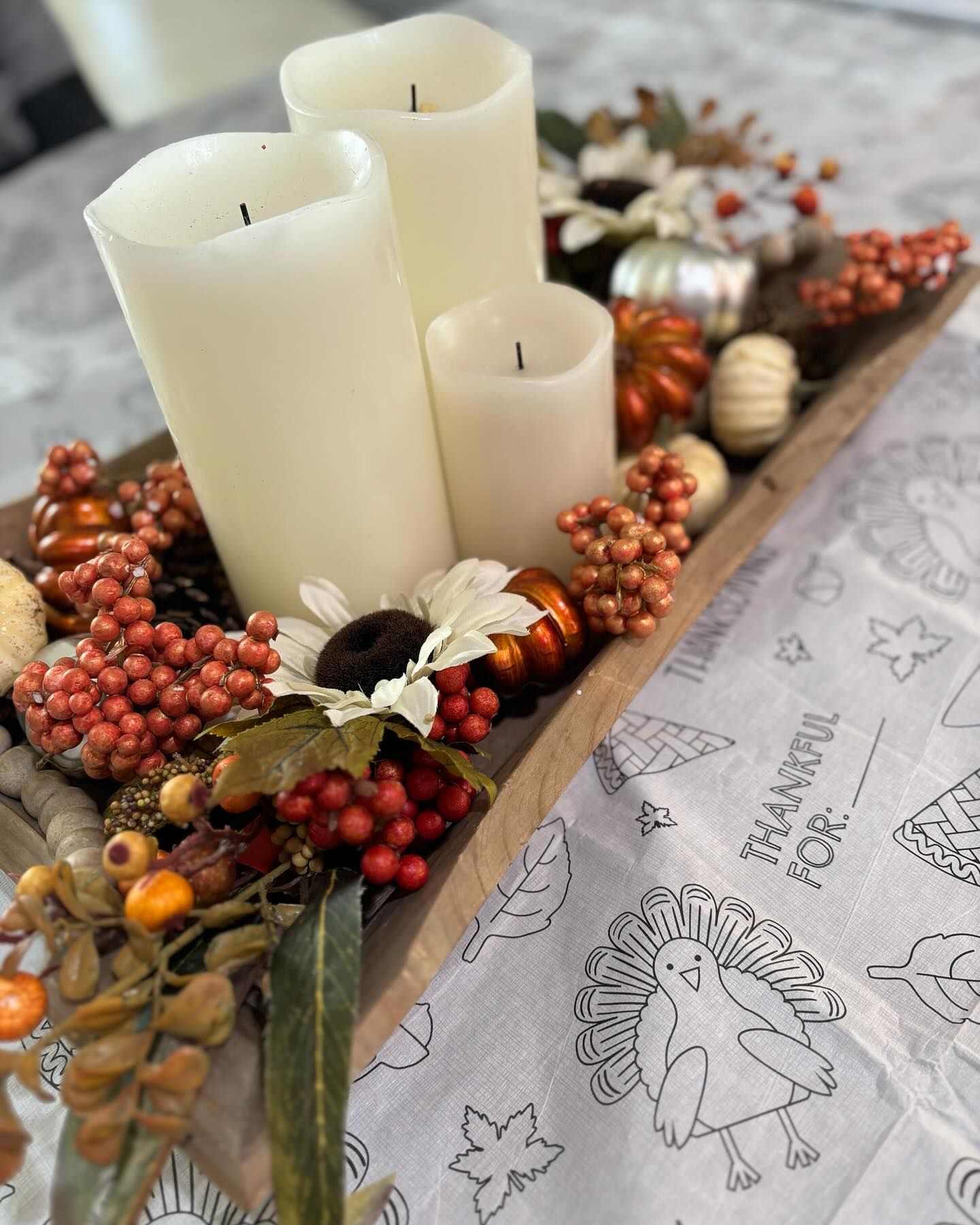 A wooden box filled with candles , pumpkins , berries and leaves on a table.
