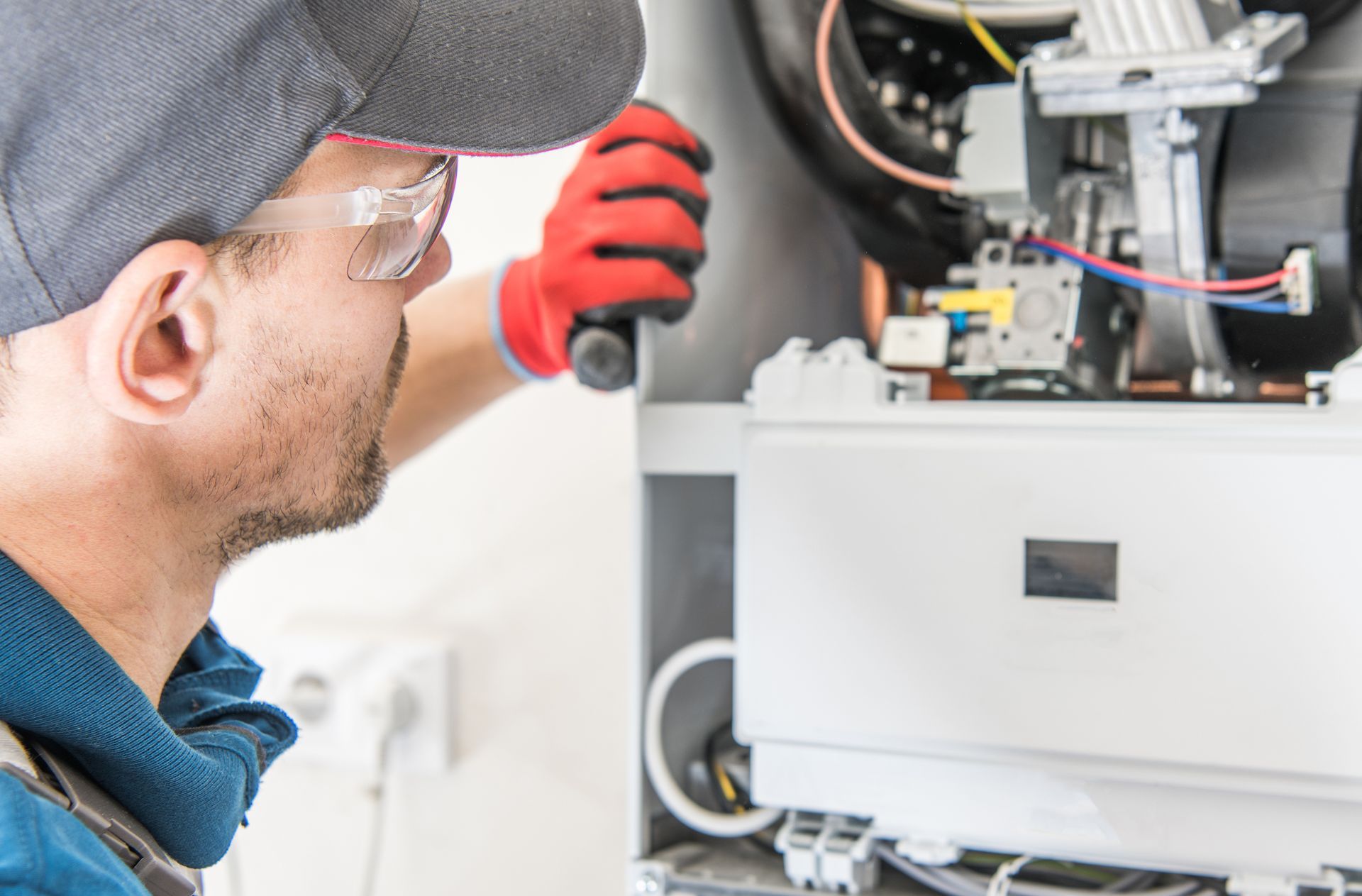 A man is fixing a boiler with a screwdriver.