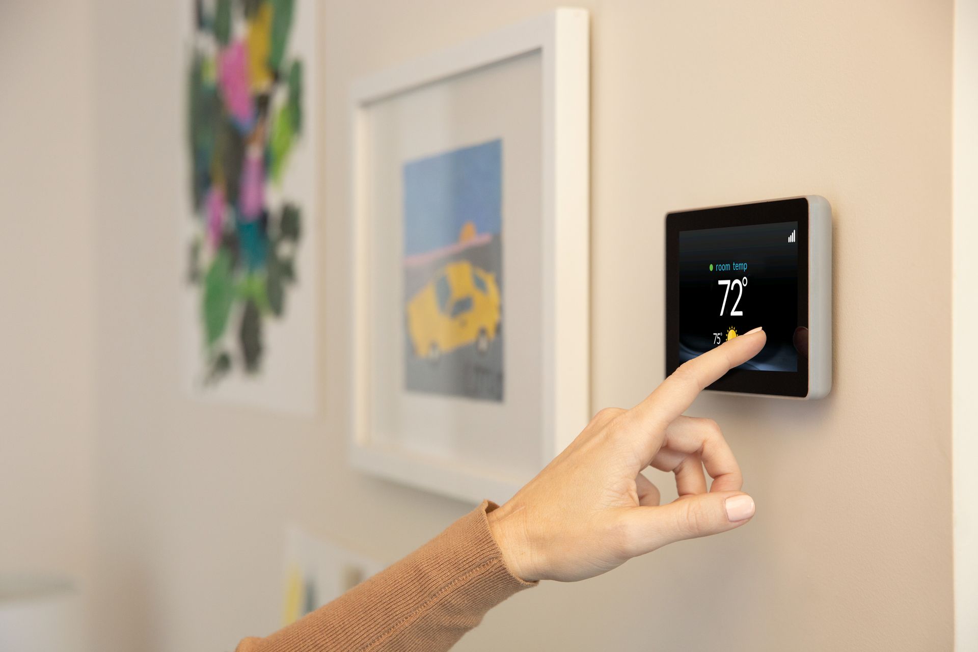 A person is pressing a button on a thermostat on a wall.