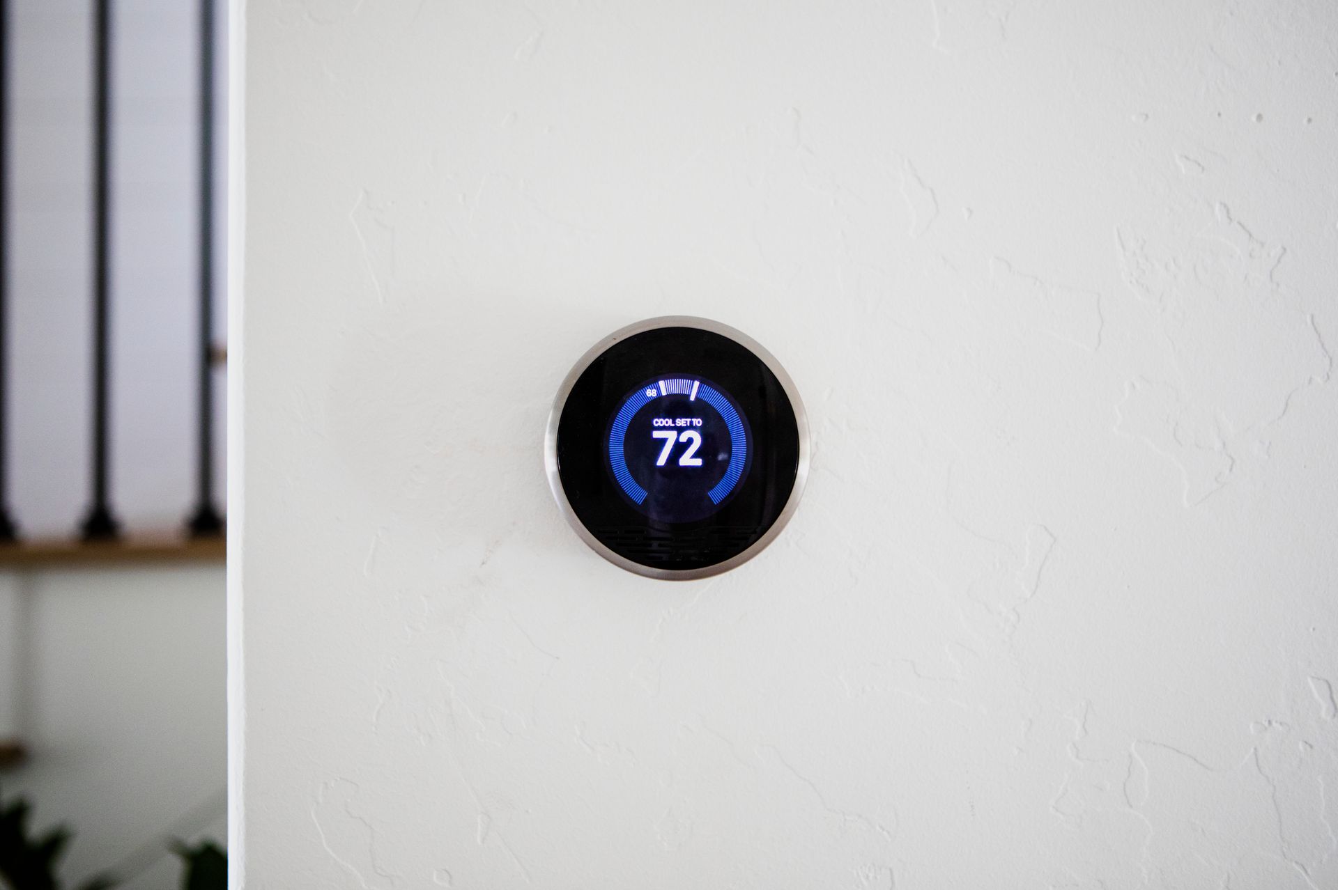 Round smart thermostat on a white wall displaying 72°