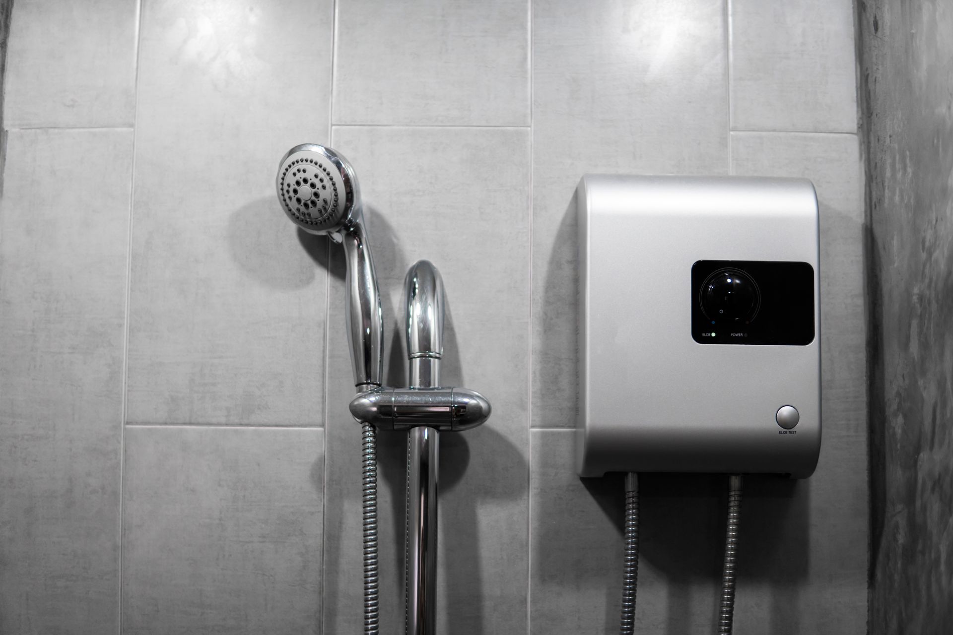 A black and white photo of a shower head and a water heater in a bathroom.