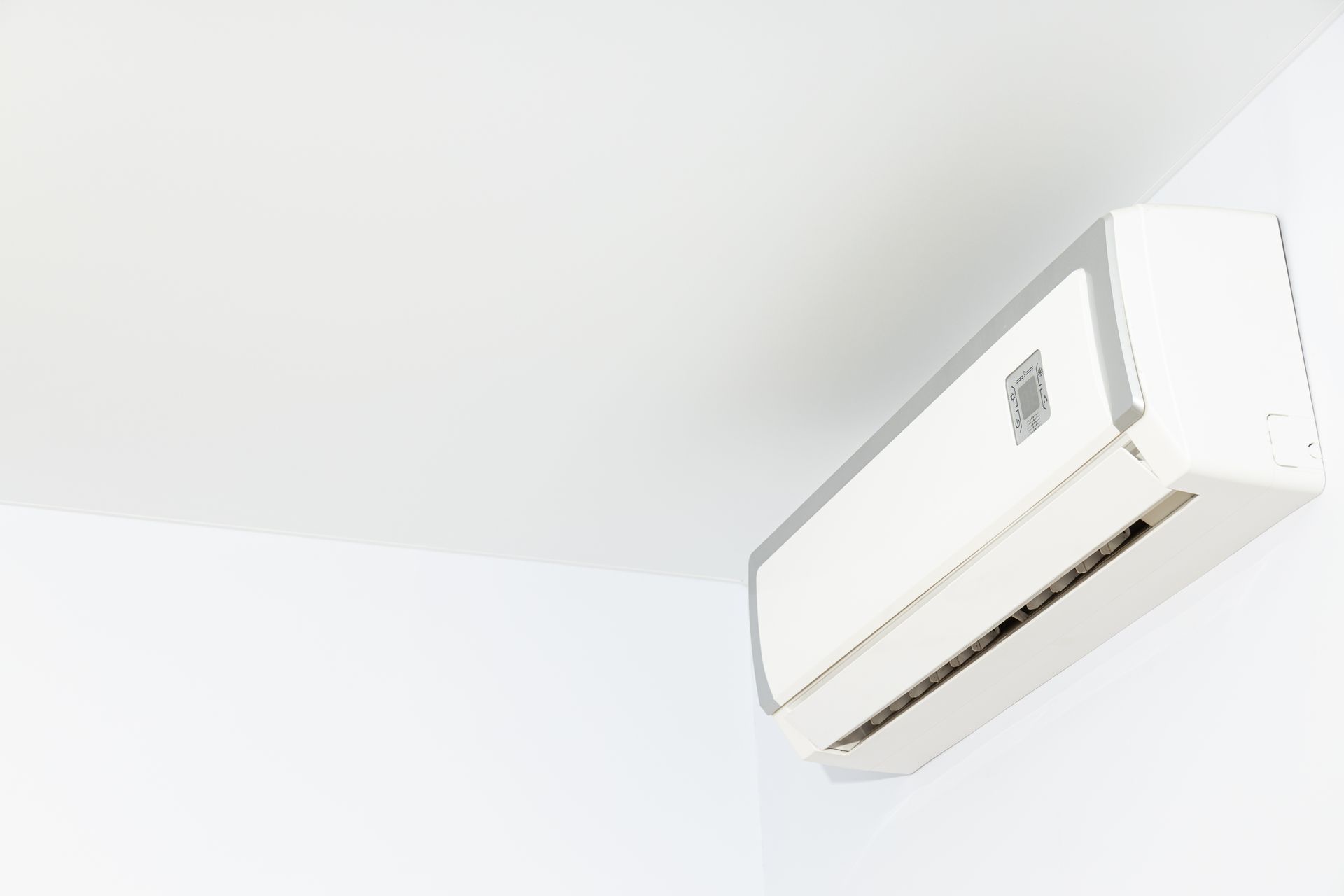 White wall-mounted air conditioner near the ceiling in a bright room