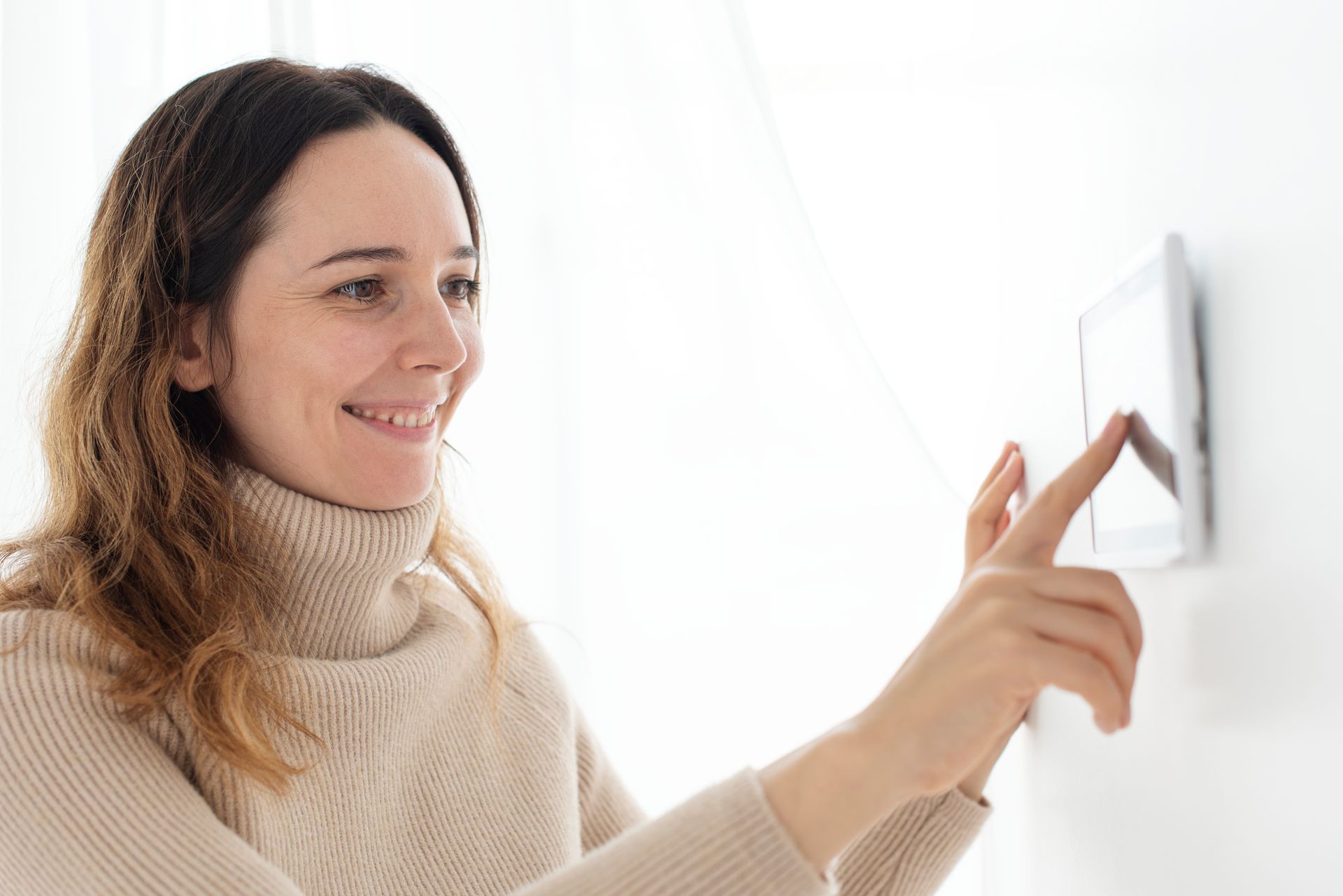 Woman smiling while pressing a wall light switch in a bright room