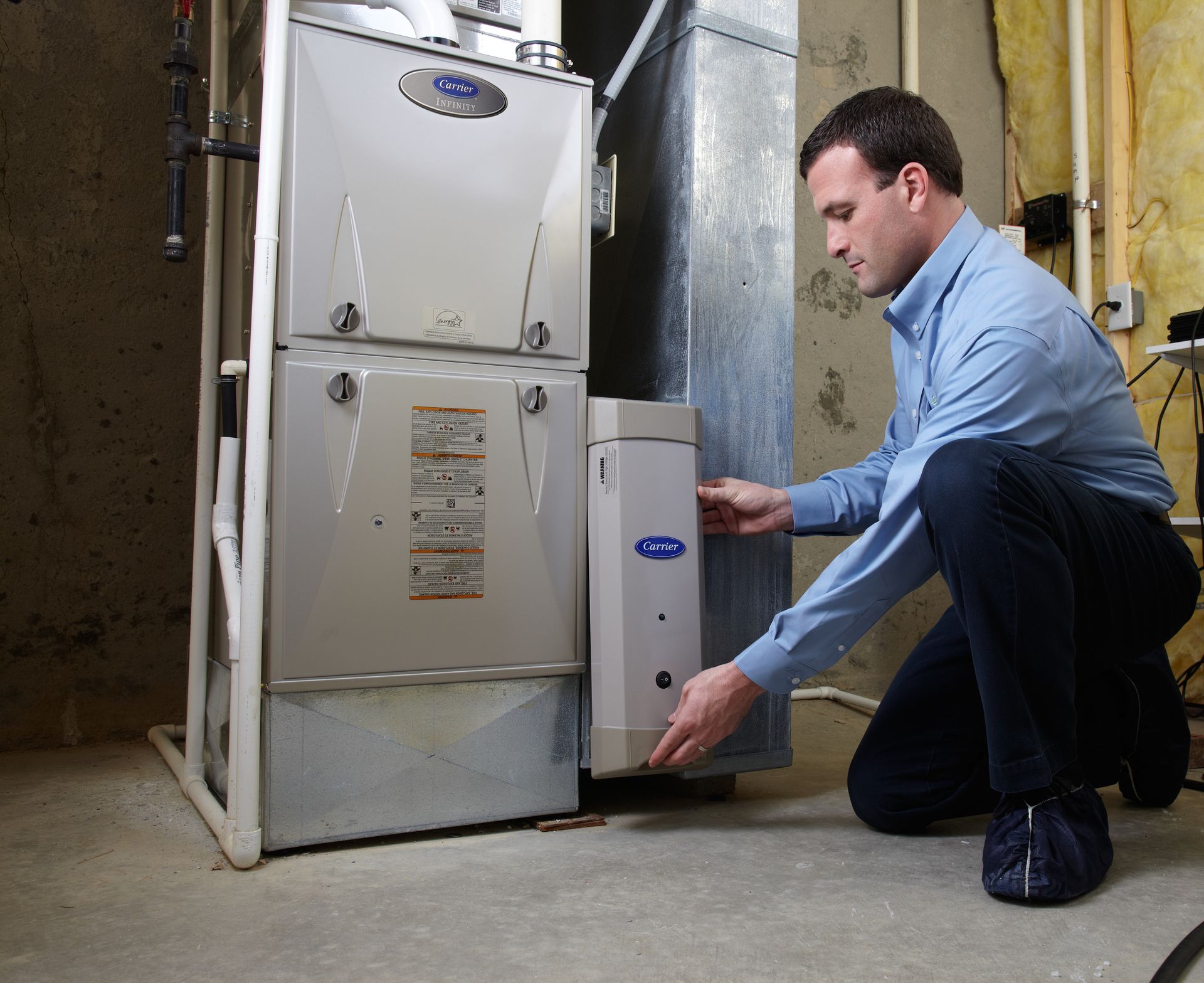 A man kneeling in front of a carrier air conditioner