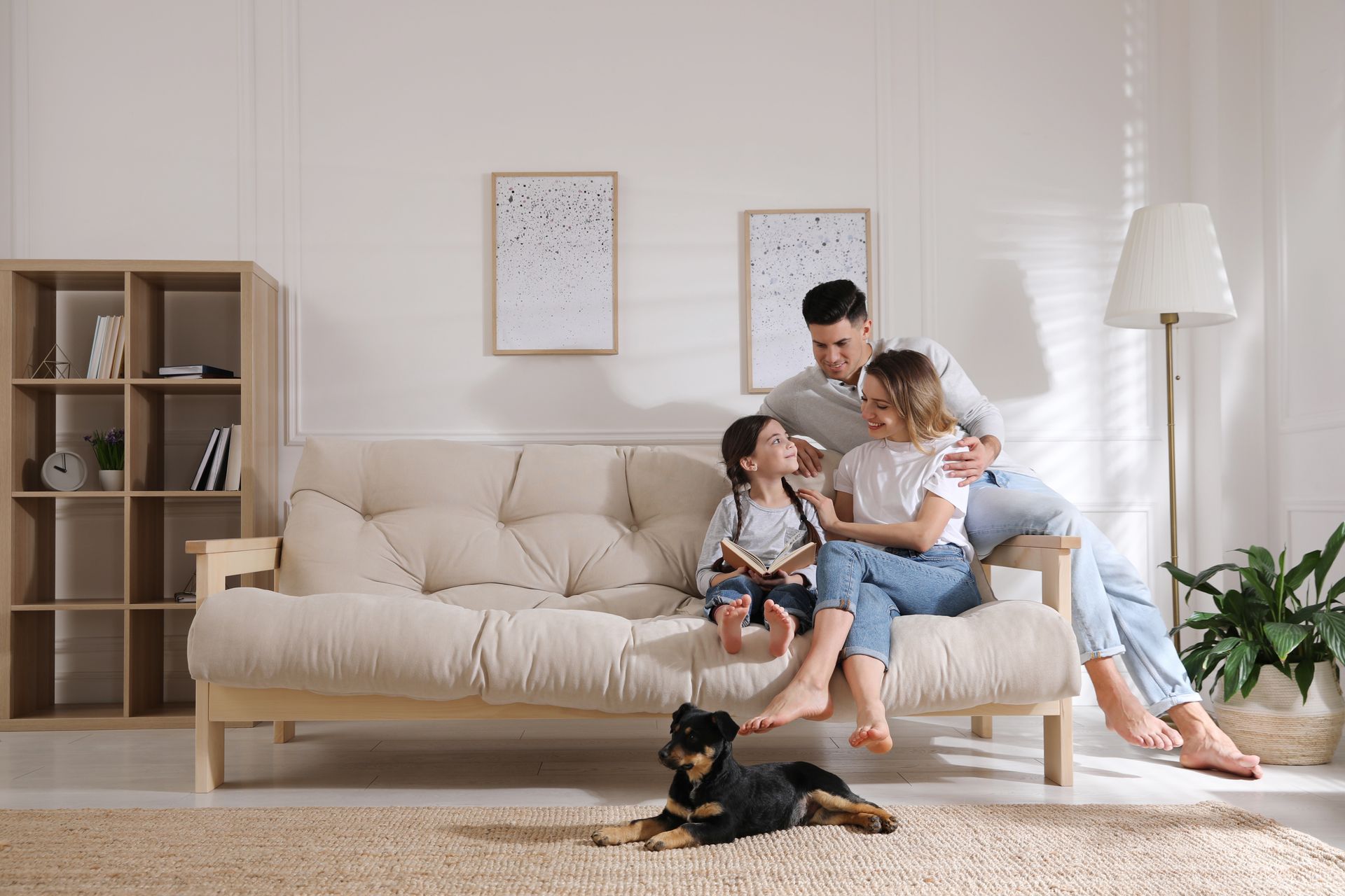 A family is sitting on a couch in a living room with a dog.