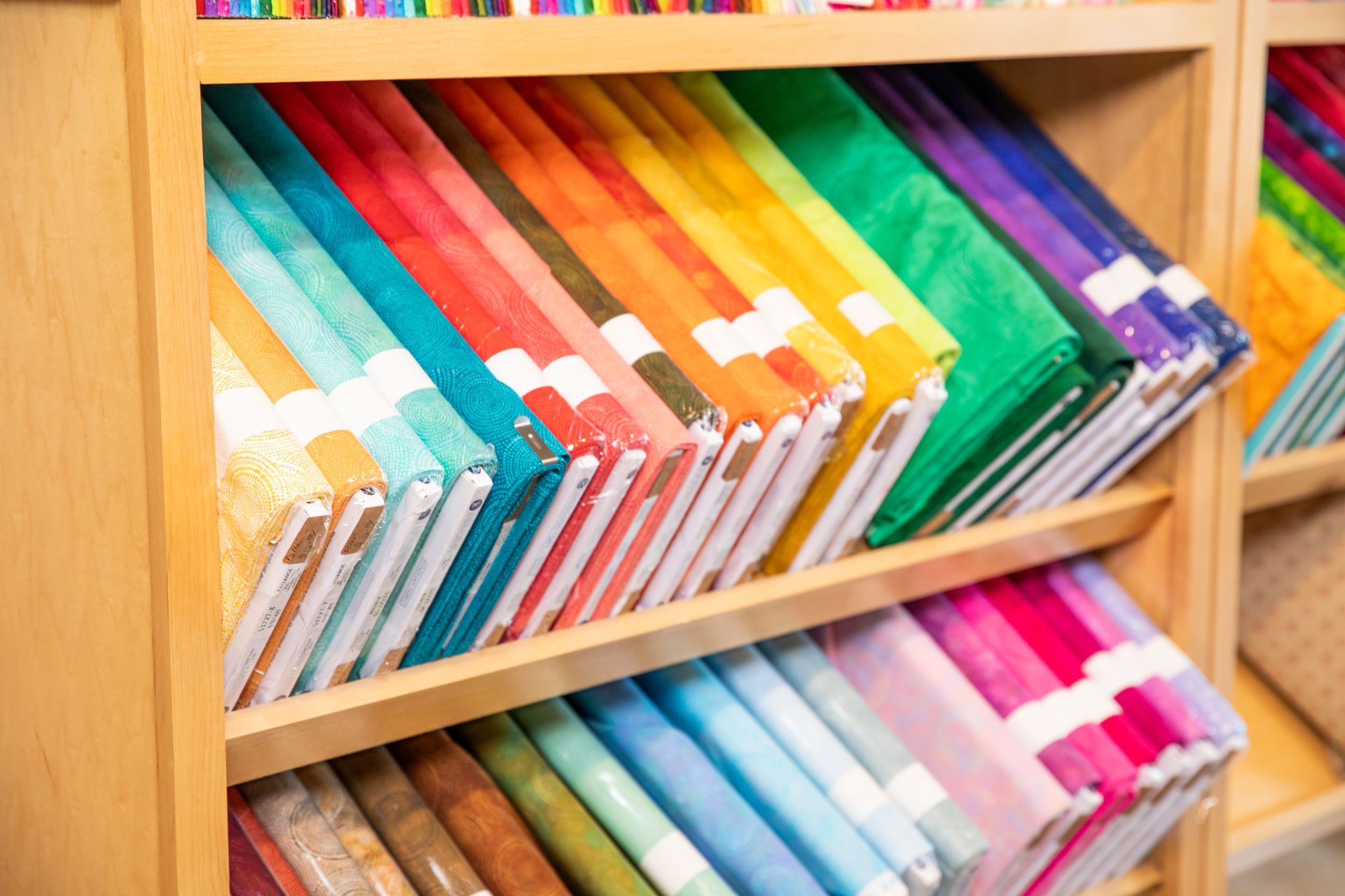 A shelf filled with lots of different colored fabrics.