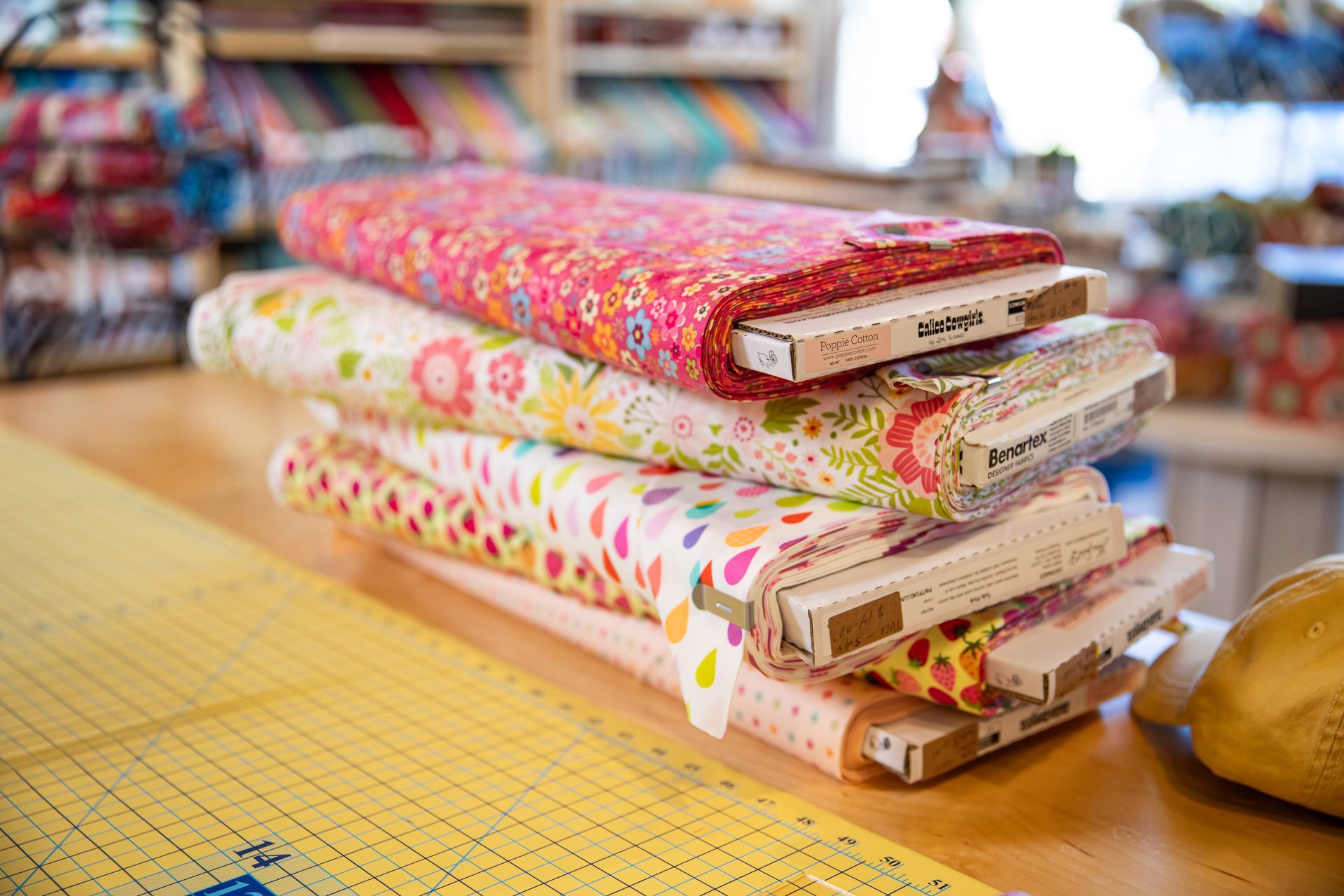 A stack of fabric rolls sitting on top of a cutting mat on a table.
