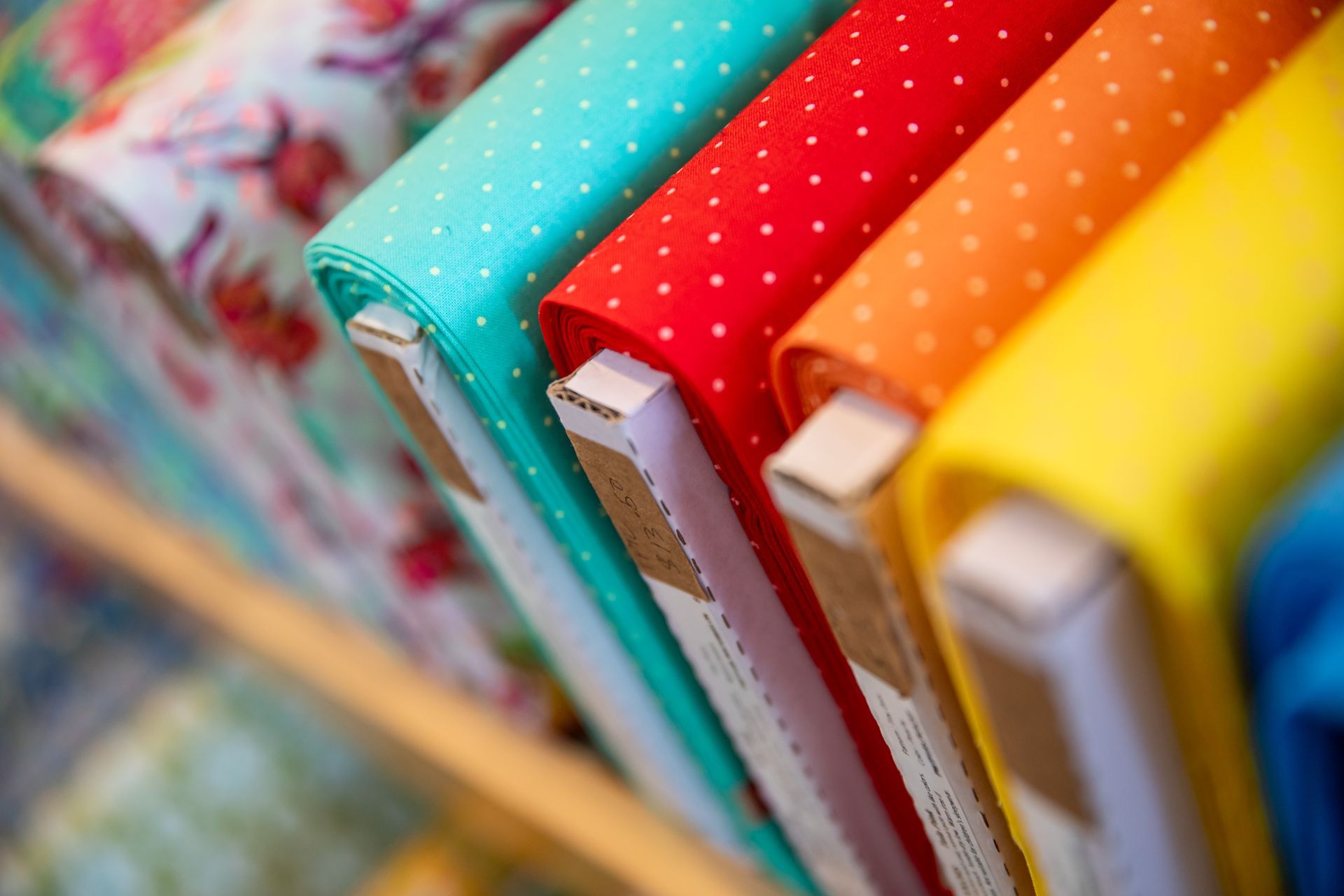 A row of colorful fabrics stacked on top of each other on a shelf.