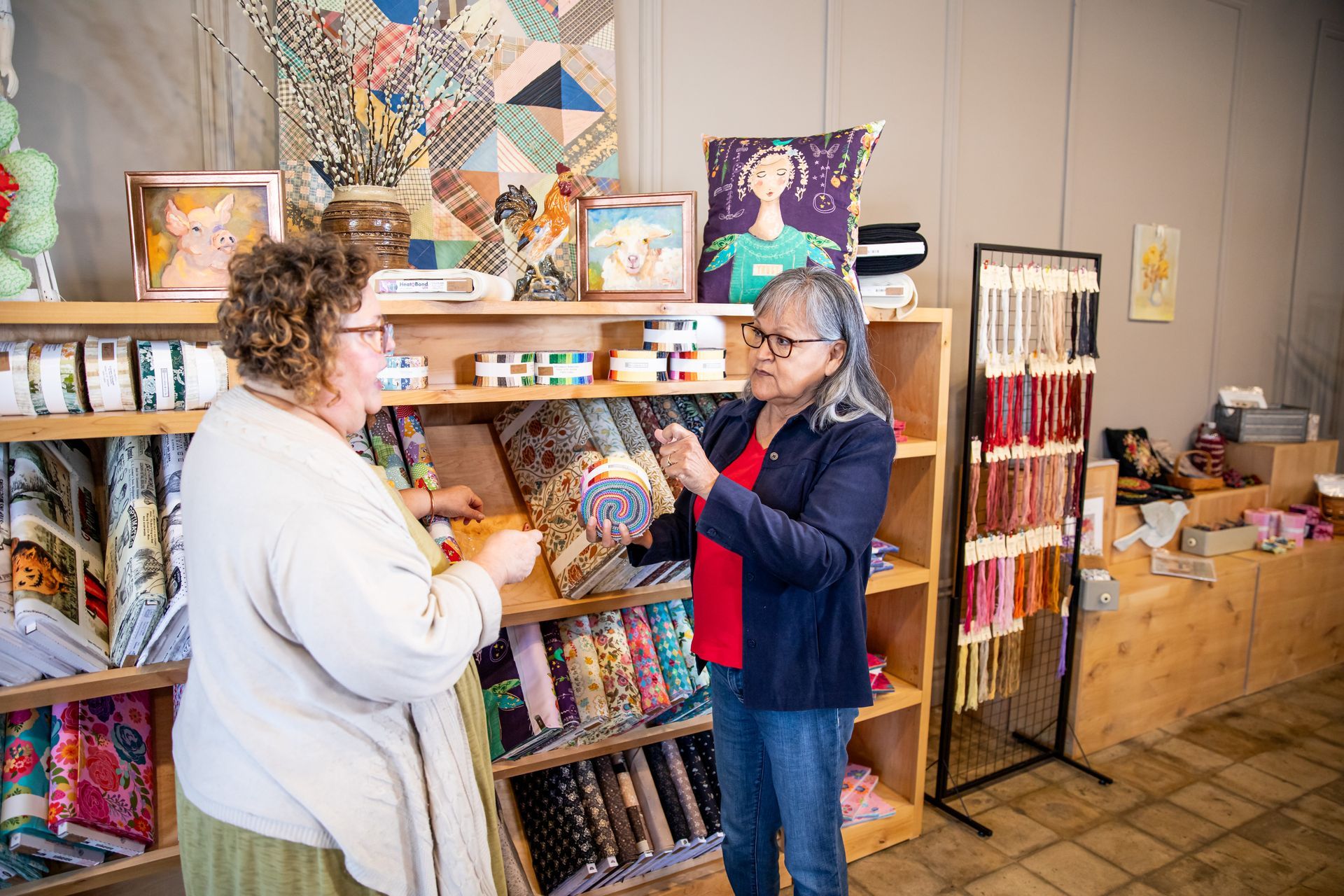 Two women are standing in a store looking at fabric.