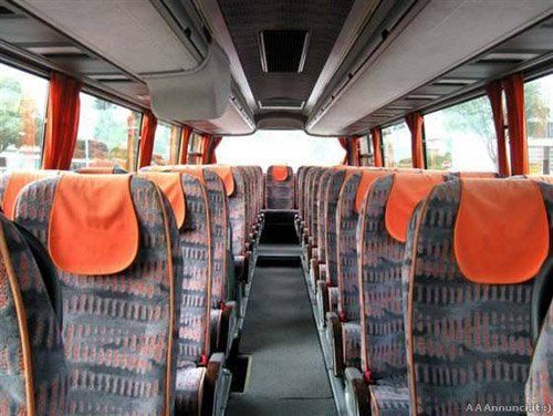 corridoio di un bus con sedili grigi e arancioni