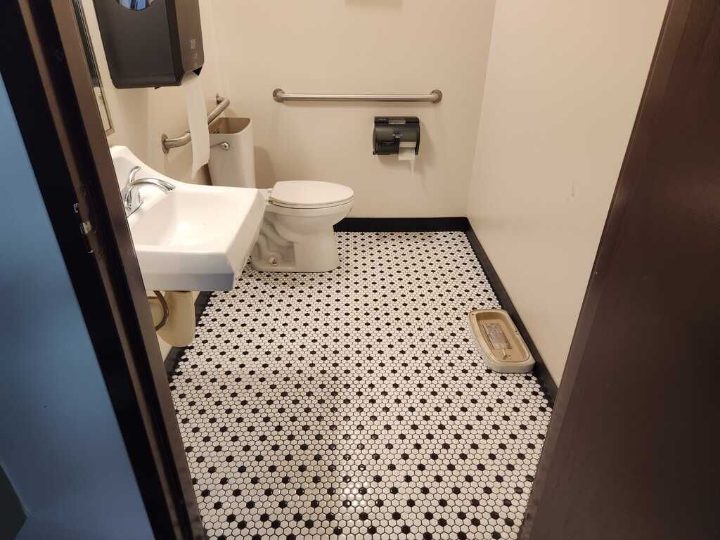 A bathroom with a toilet , sink , and black and white tile floor.