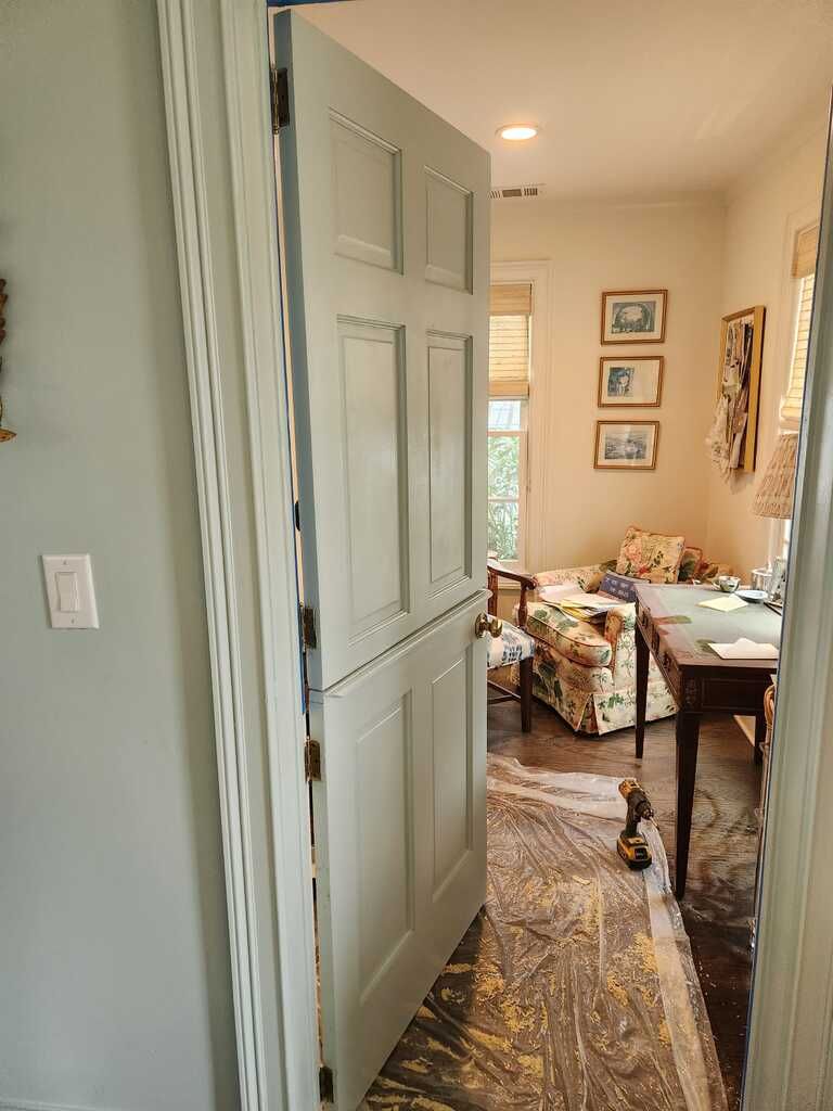 A door is open to a living room with a couch and a desk.