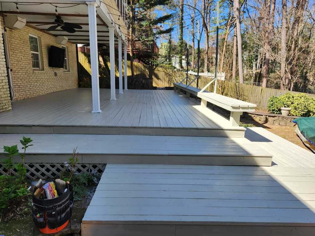 A large wooden deck with stairs leading up to it in front of a house.