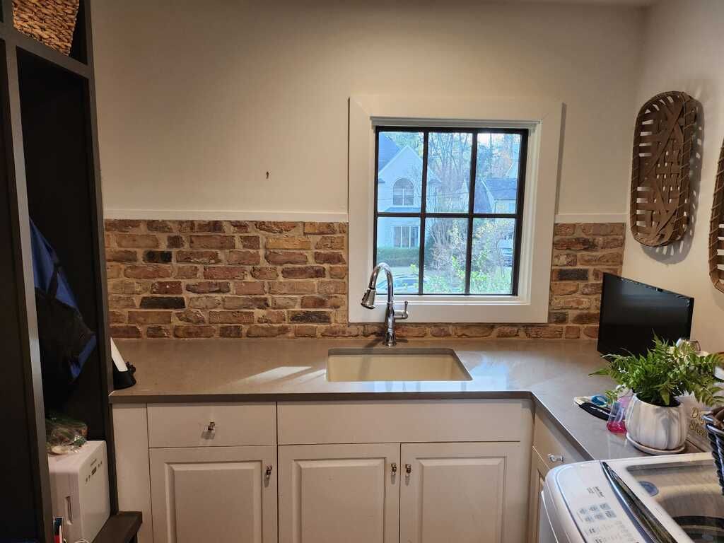 A laundry room with a sink , washer and dryer , and a window.