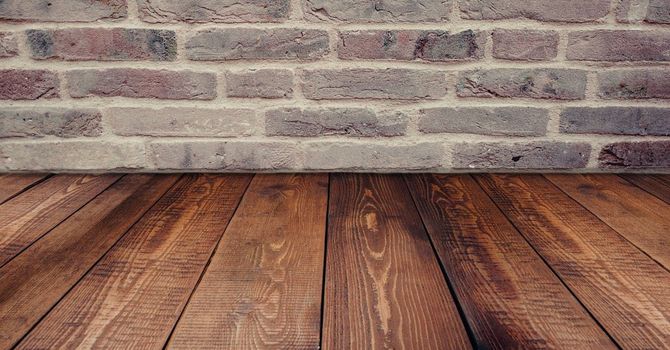 There is a wooden floor in front of a brick wall.