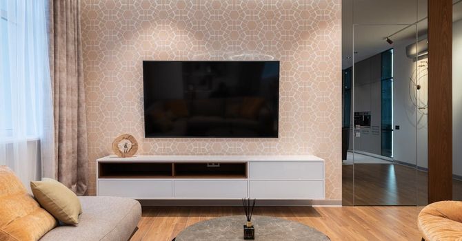 A living room with a couch and a flat screen tv on the wall.