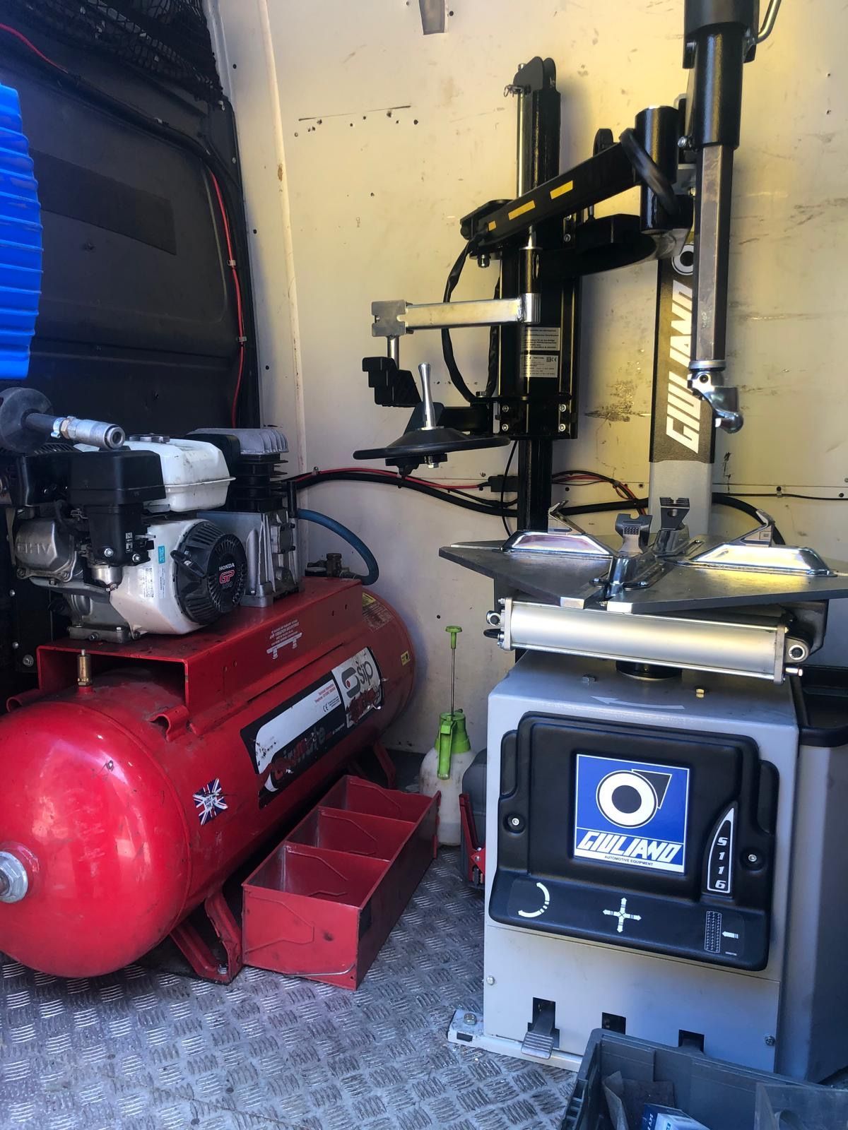 Inside a van: tire changing machine and air compressor in a repair vehicle.