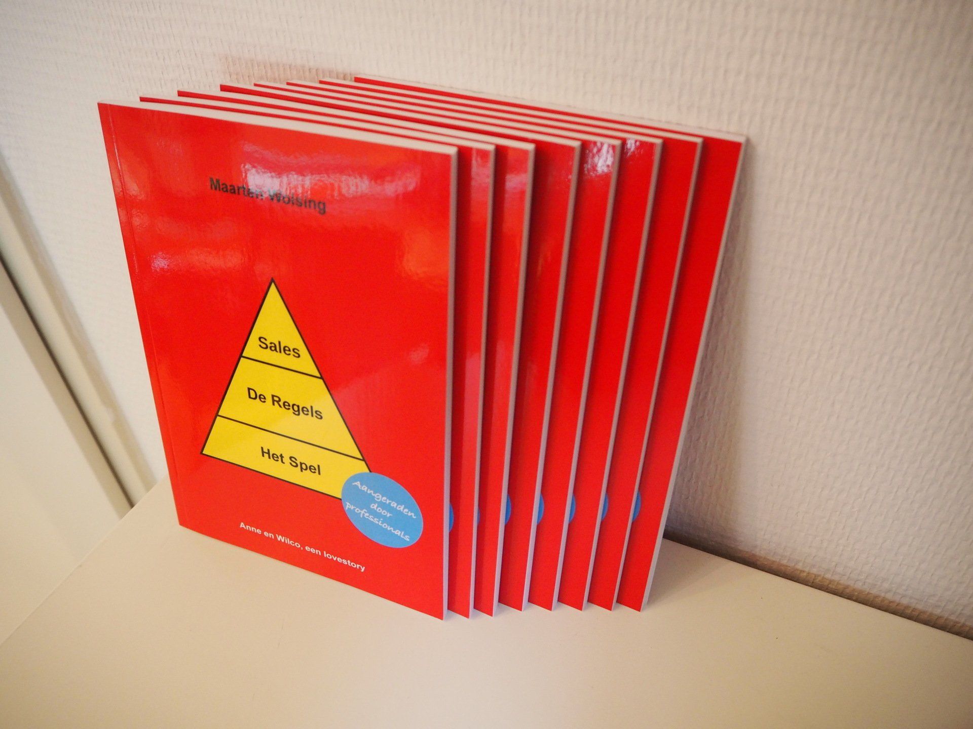 Een stapel rode boeken met een gele driehoek op de omslag