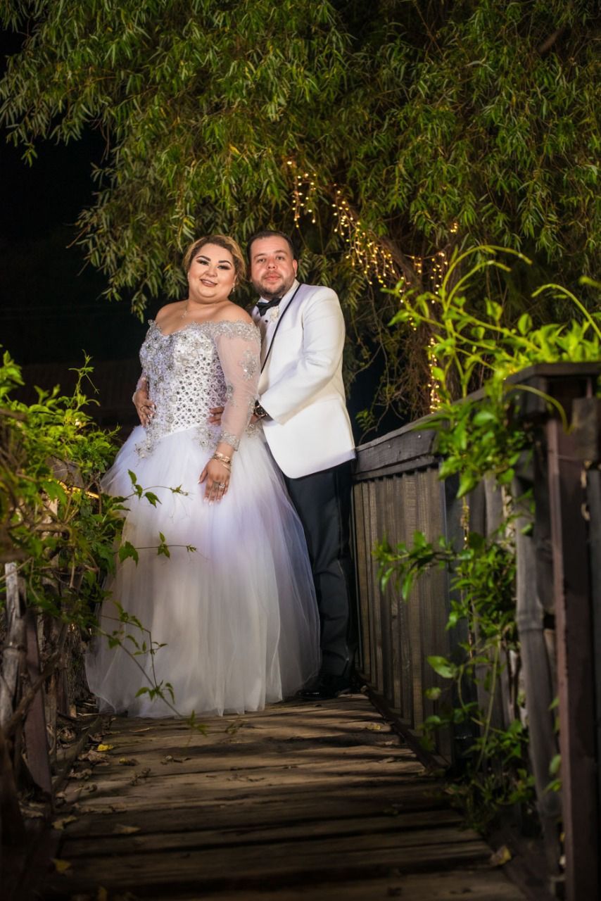 Una novia y un novio posan para una foto en un puente de madera.