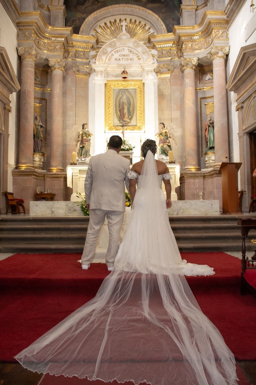 Una novia y un novio están de pie frente a un altar en una iglesia.