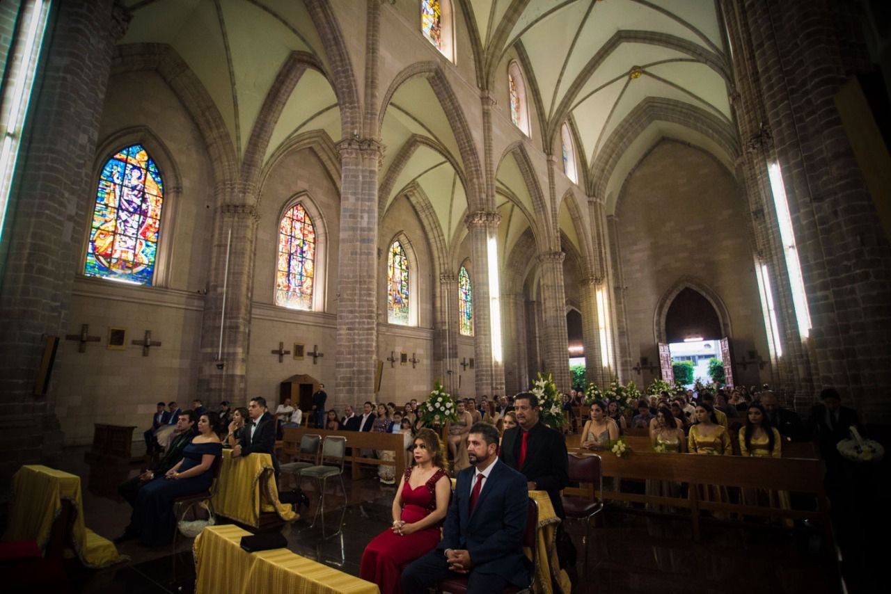 Un grupo de personas está sentada en una iglesia viendo una ceremonia de boda.