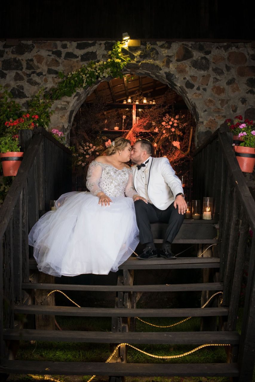 Una novia y un novio se besan en las escaleras de un puente.