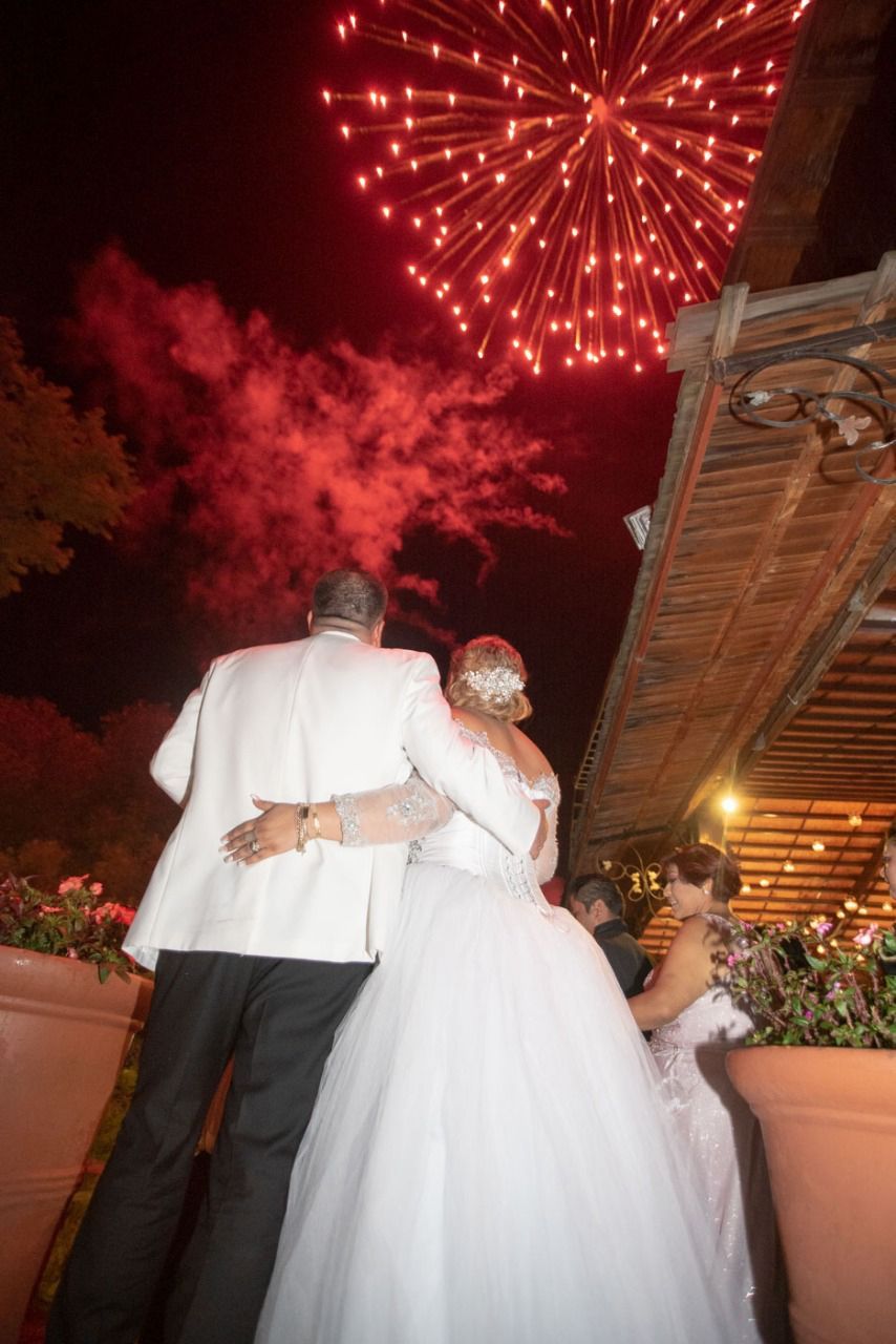 Una novia y un novio están viendo fuegos artificiales en su boda.