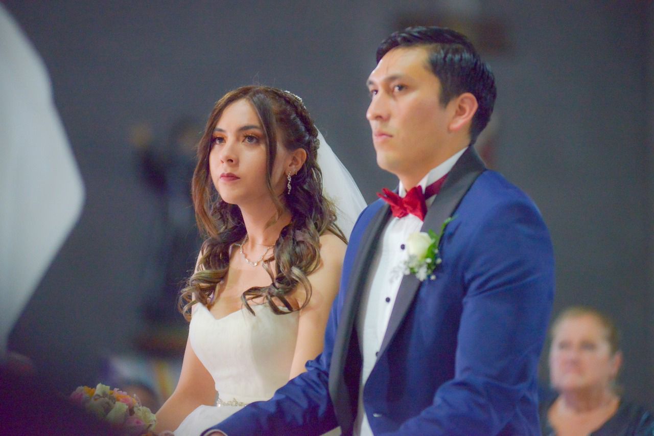 Una novia y un novio se toman de la mano durante su ceremonia de boda en una iglesia.
